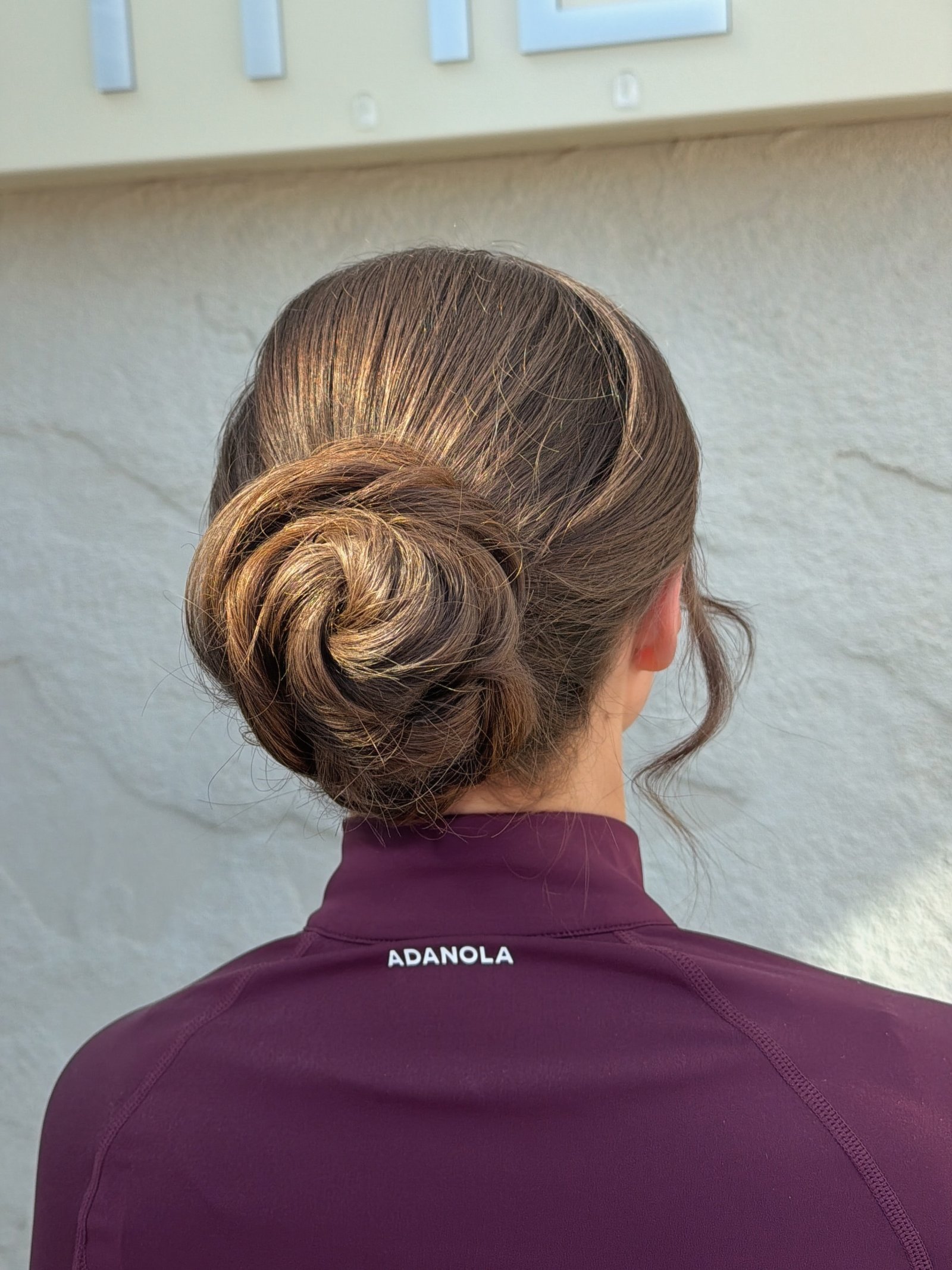 Low coiled gym bun with a sleek crown