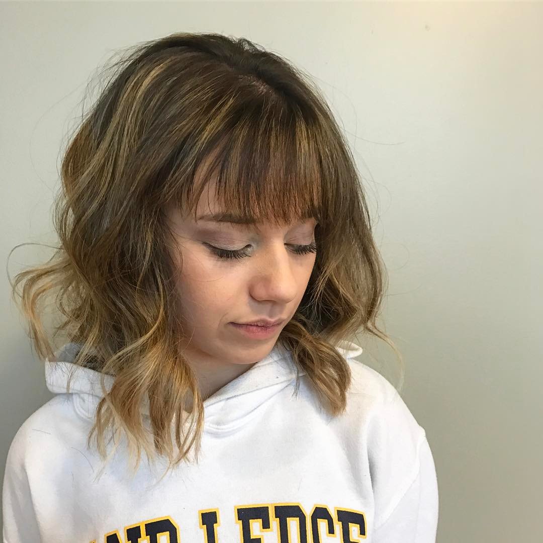 Layered shoulder-length haircut with wispy fringe and face-framing waves