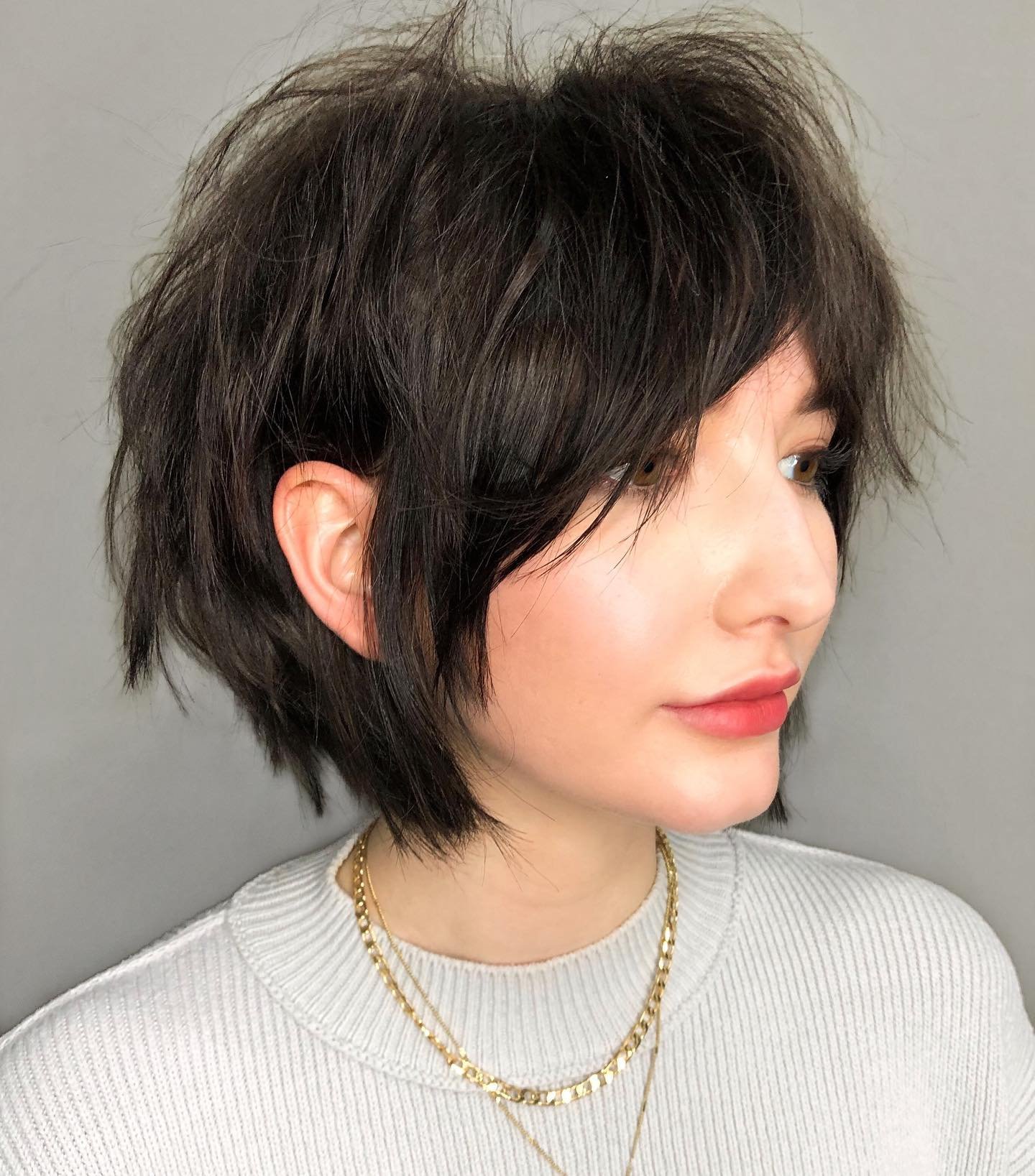Shaggy black bixie with long side-swept fringe and feathered nape