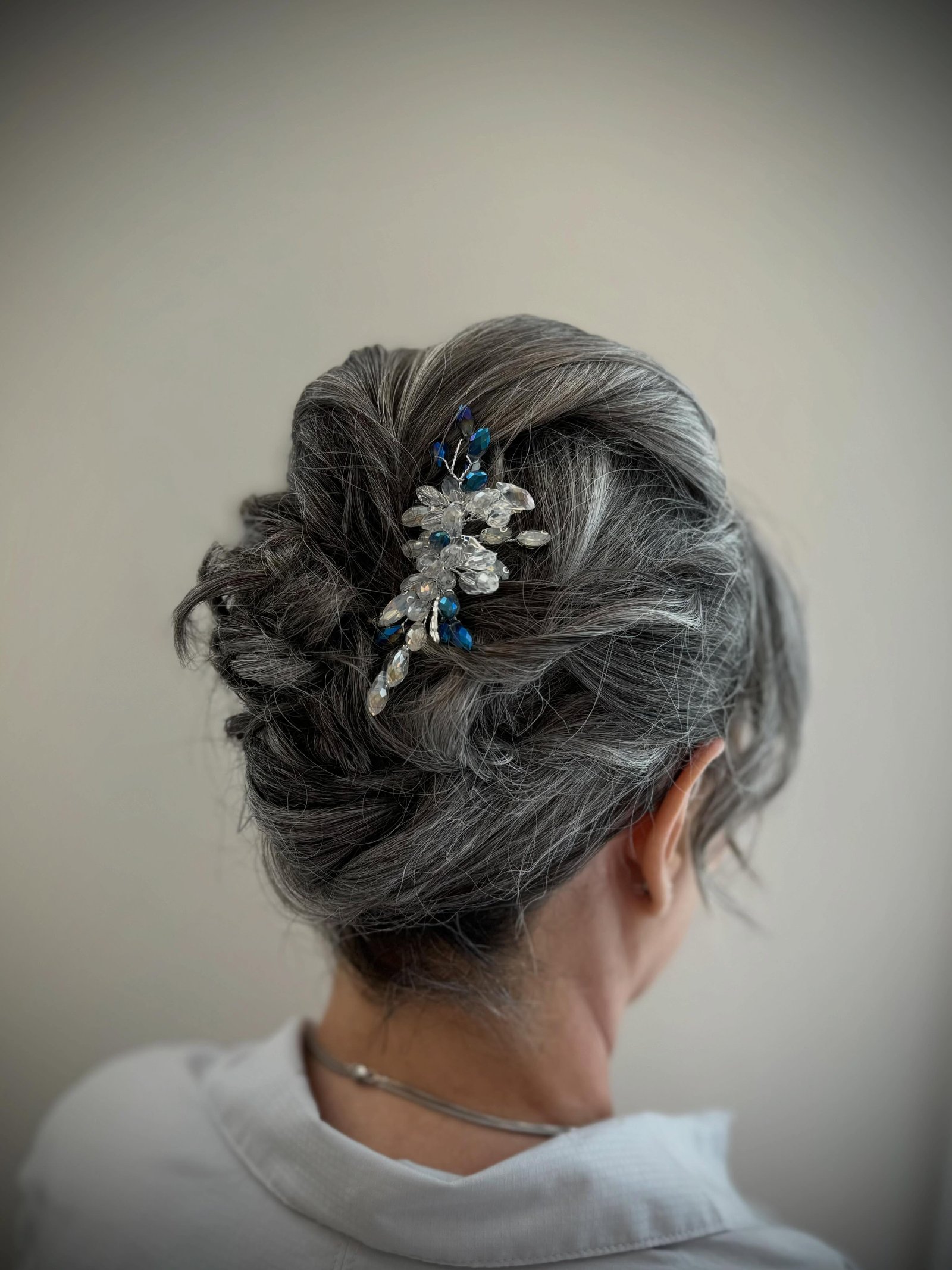 Textured dark grey bun decorated with a blue and silver jeweled hairpiece
