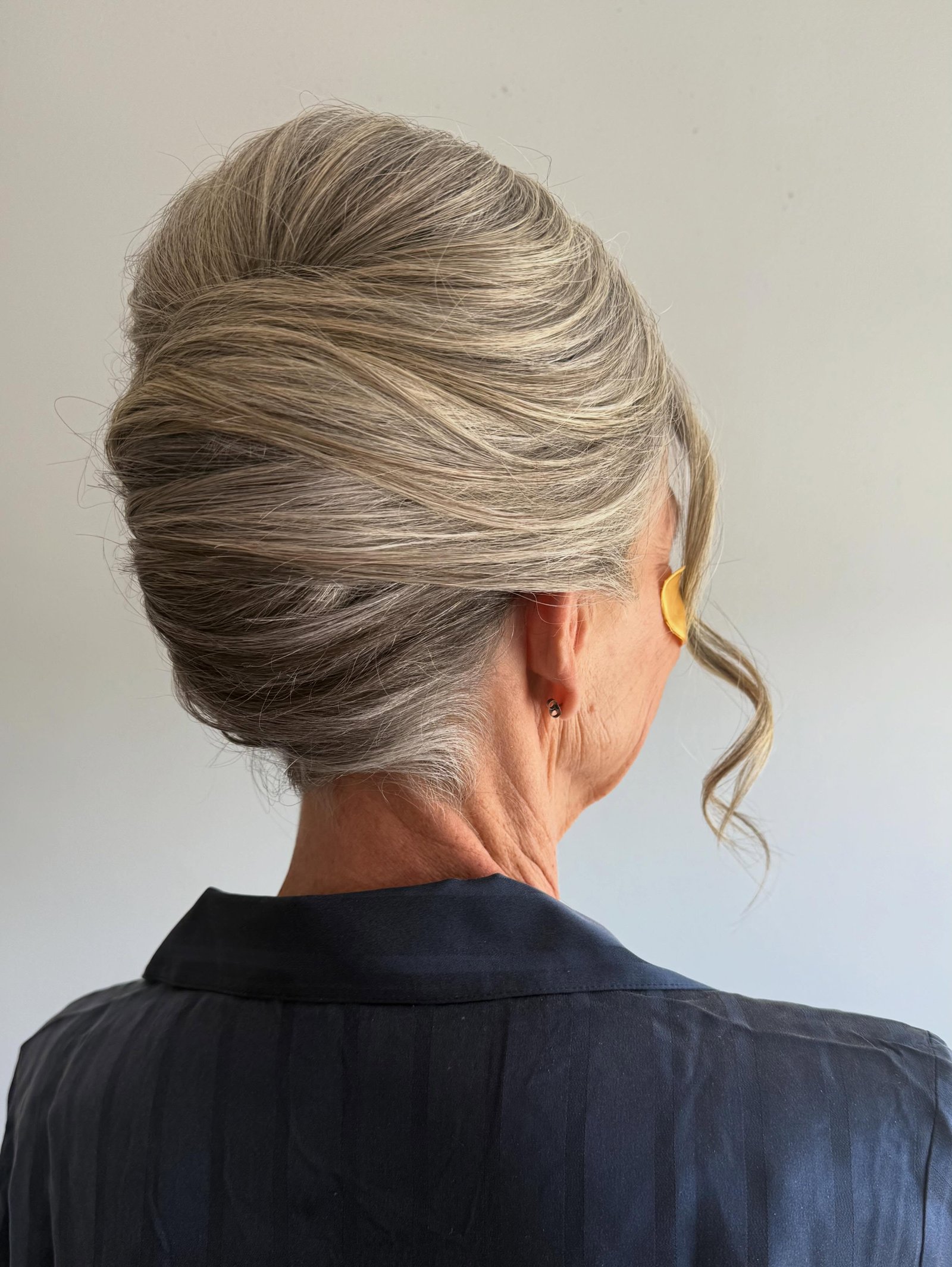 Classic smooth French twist with a single curled face-framing tendril