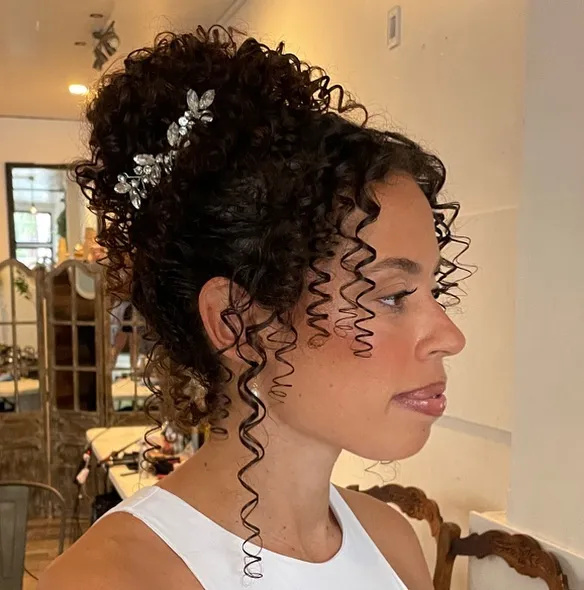 High curly bridal updo with silver floral pins and long face-framing ringlets