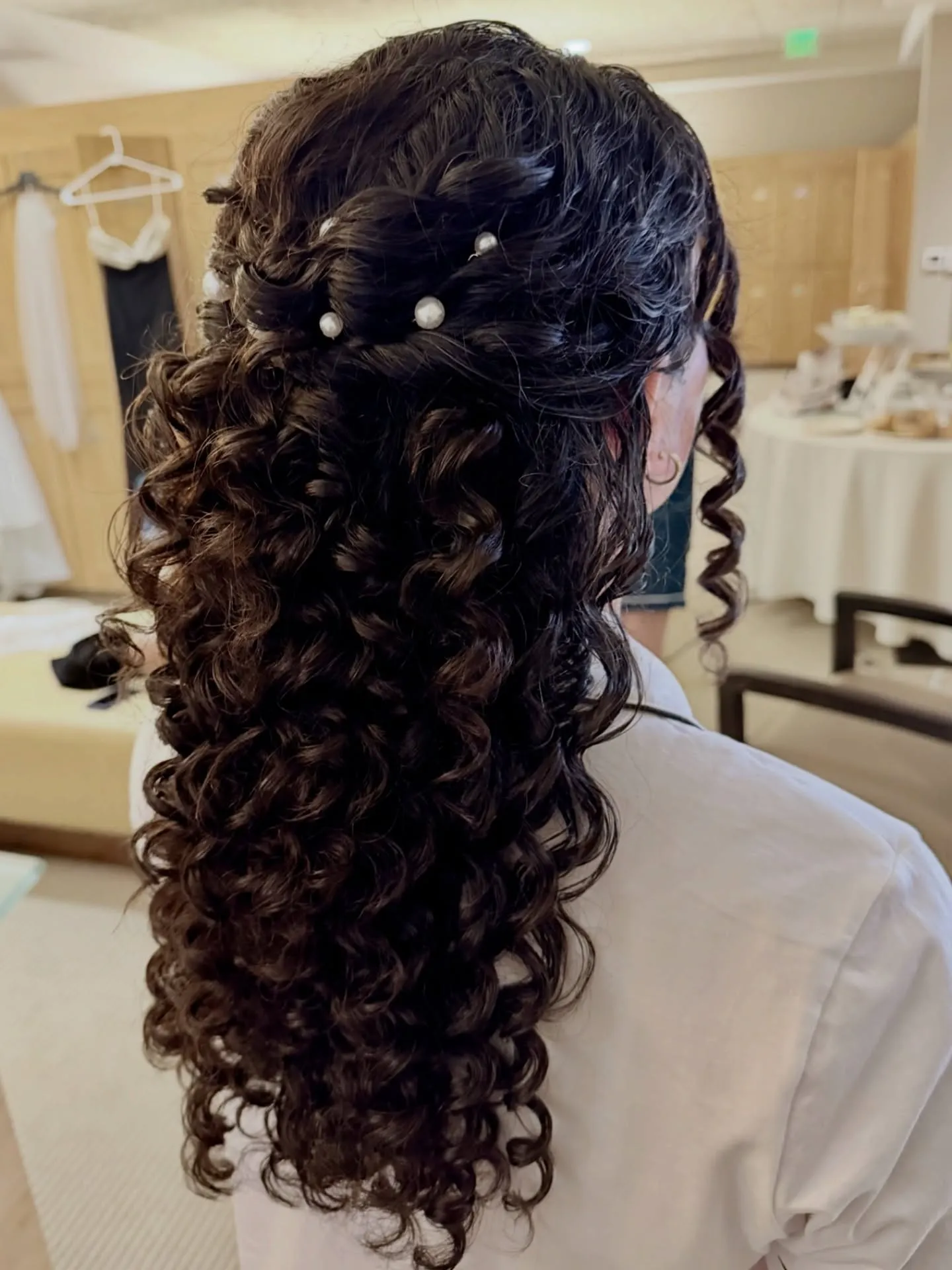 Long curly half-up bridal hairstyle with scattered pearl pins and loose ringlets