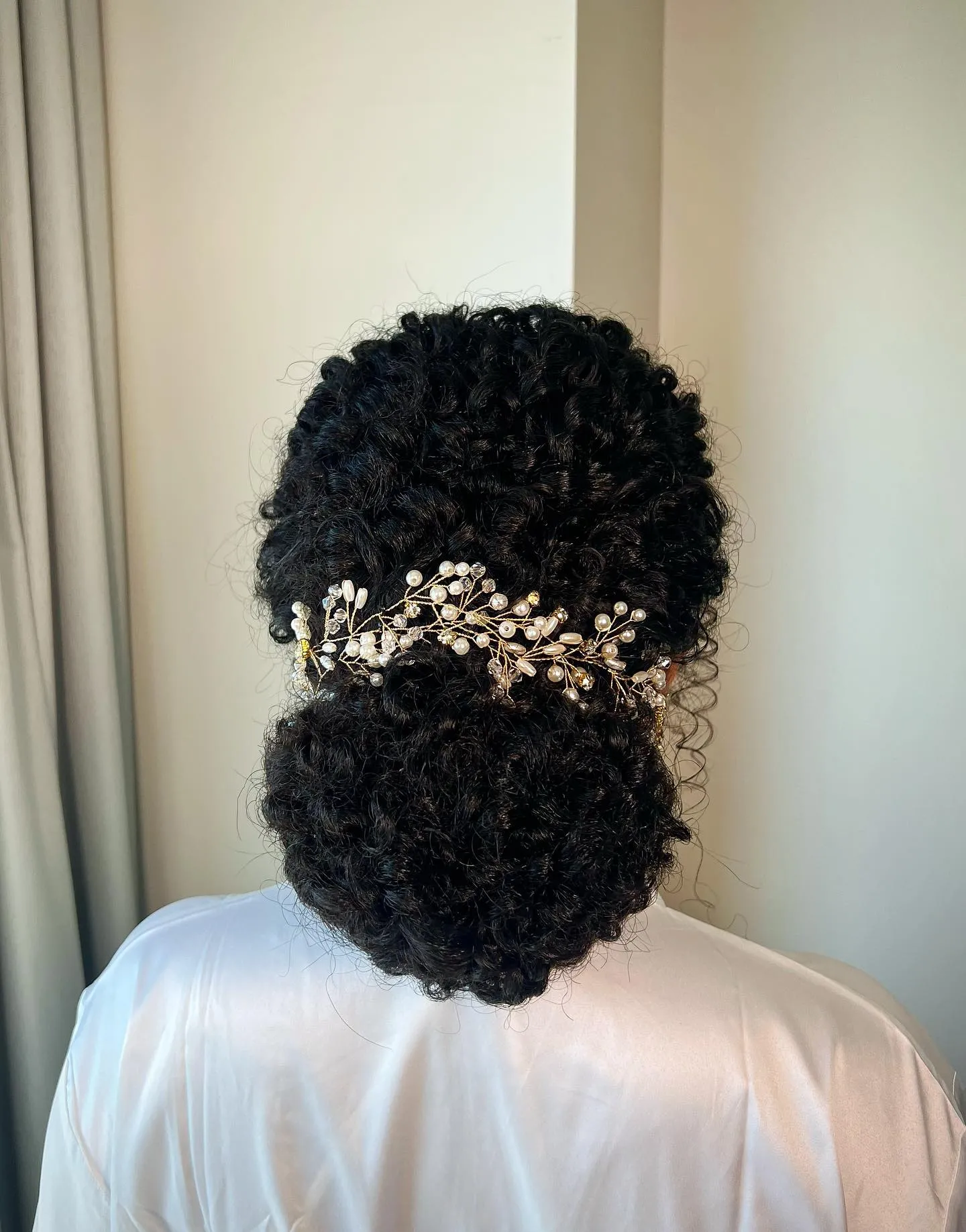 Rounded textured bridal updo with crystal leaf vine across the centre