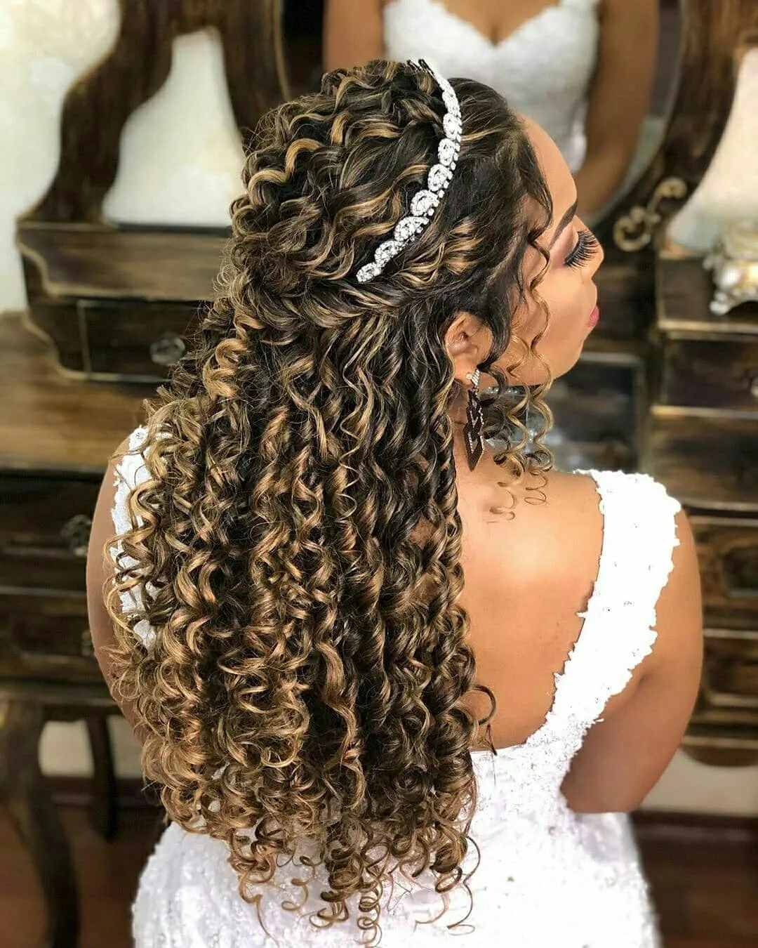 Long curly half-up bridal hairstyle with crystal headband and face-framing curls