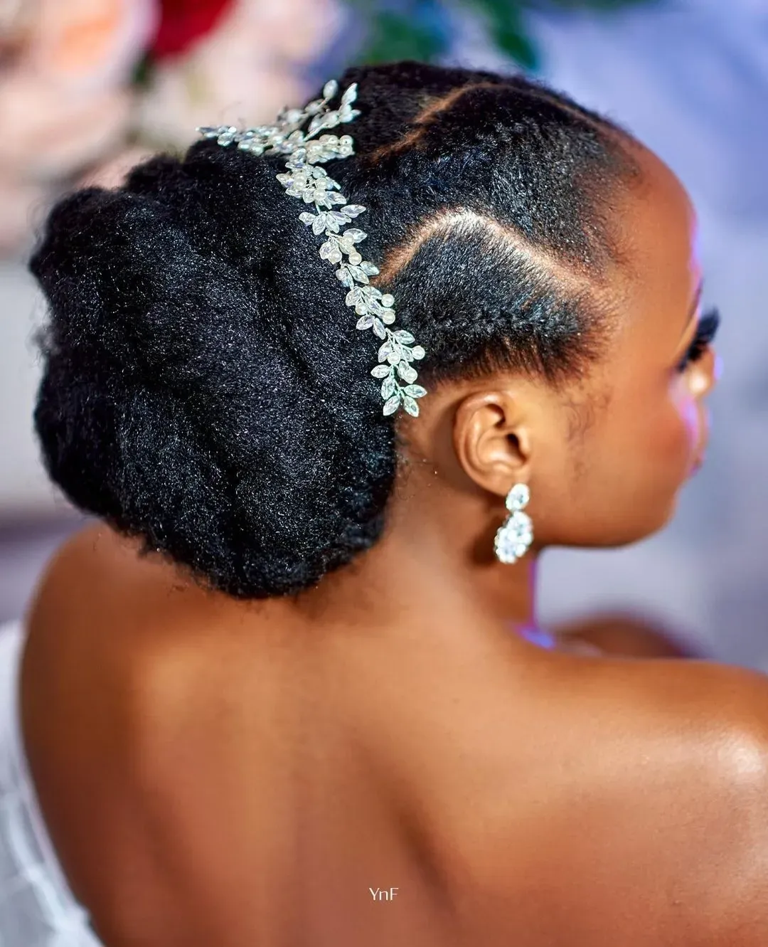 Sleek low bridal puff with sculpted parting and silver leaf hair vine