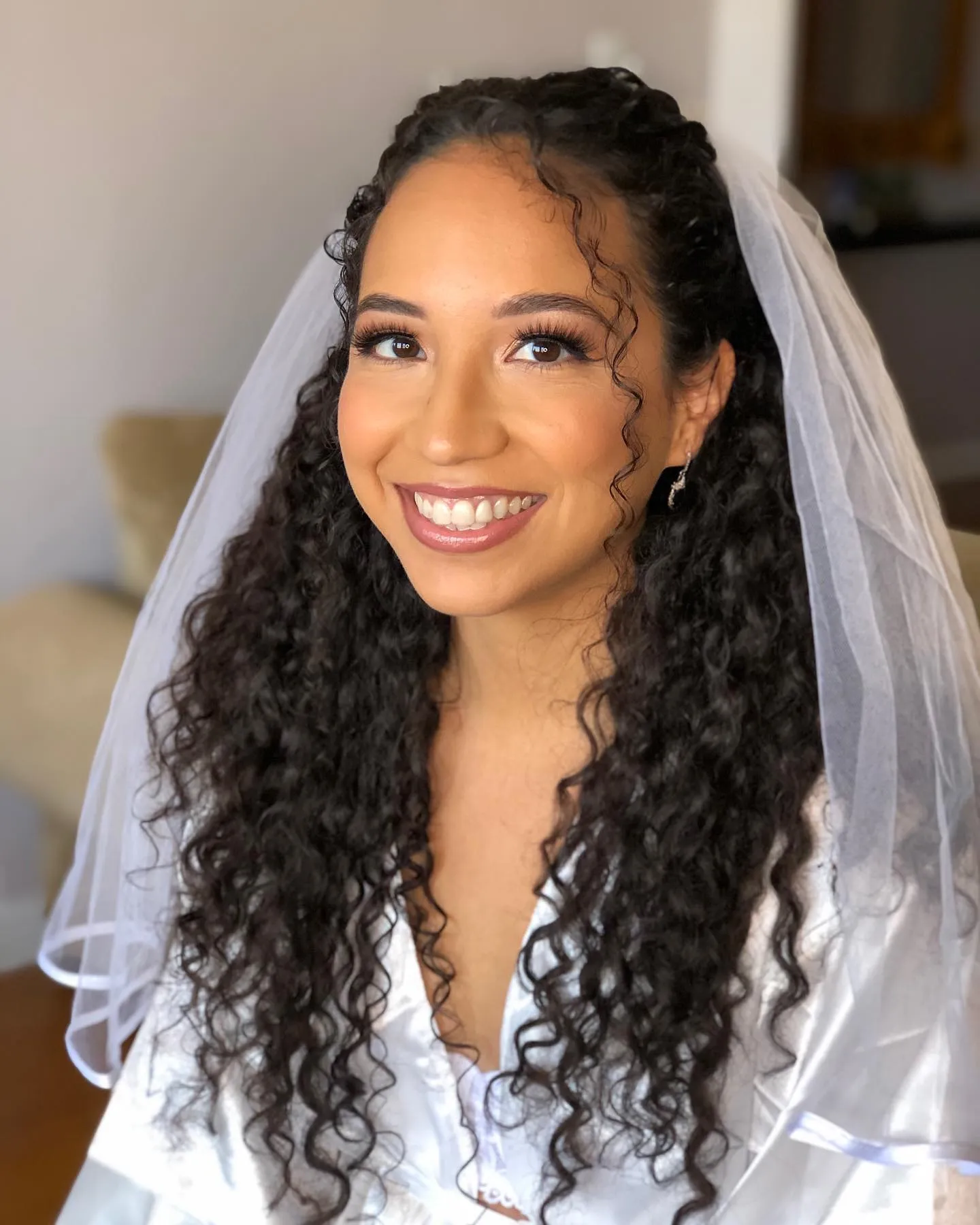 Long loose bridal curls with centre braids, curled tendrils and a veil