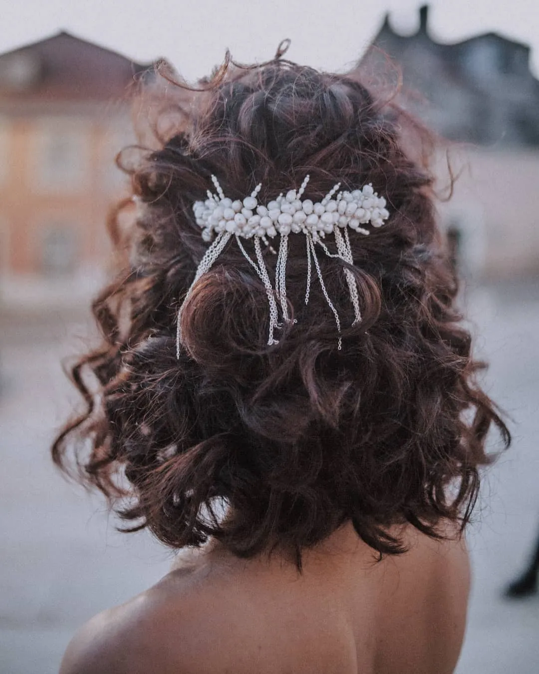 Curly half-up bridal bob with pearl comb and delicate draped chains