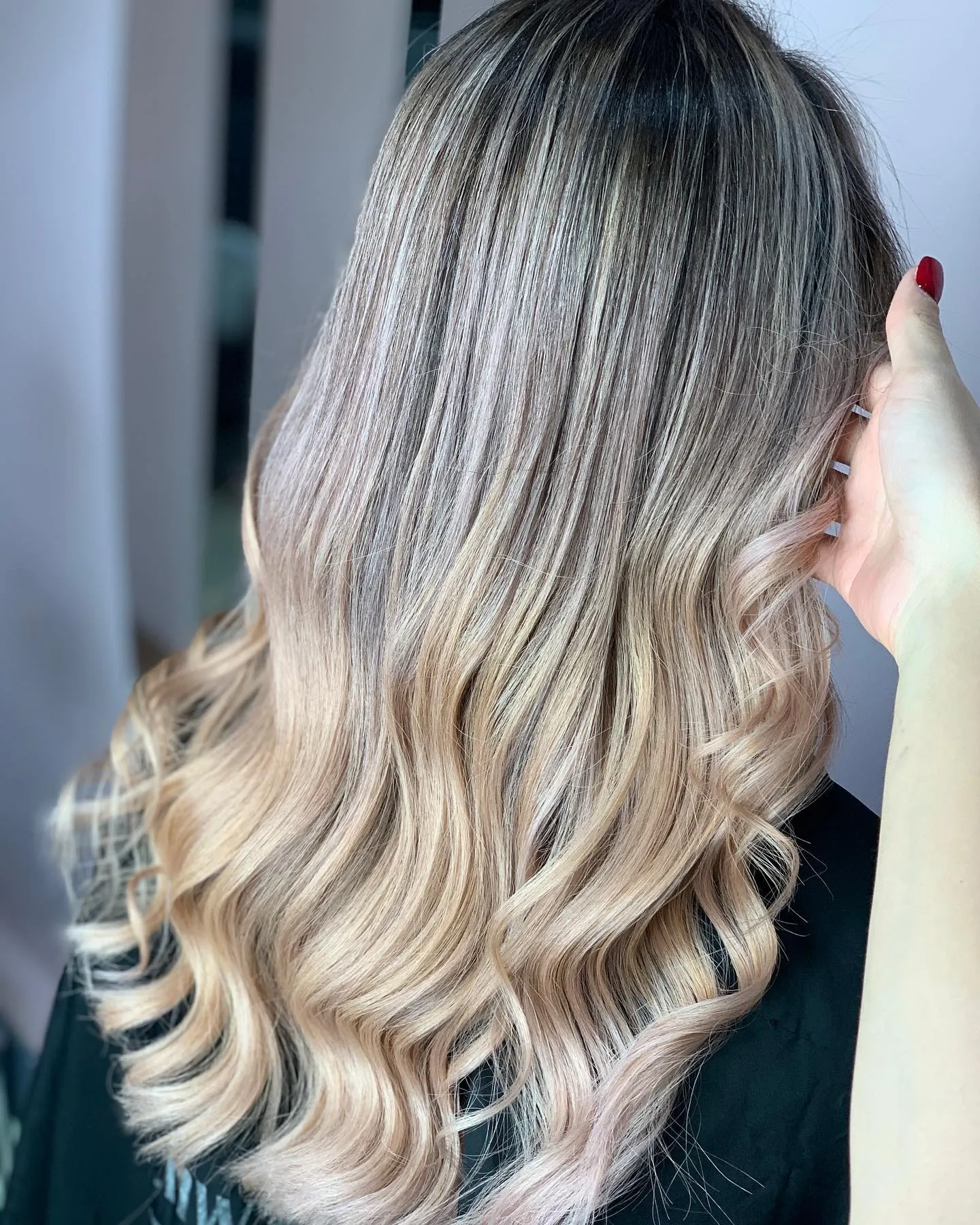 Cool blonde balayage with dark roots and soft waves