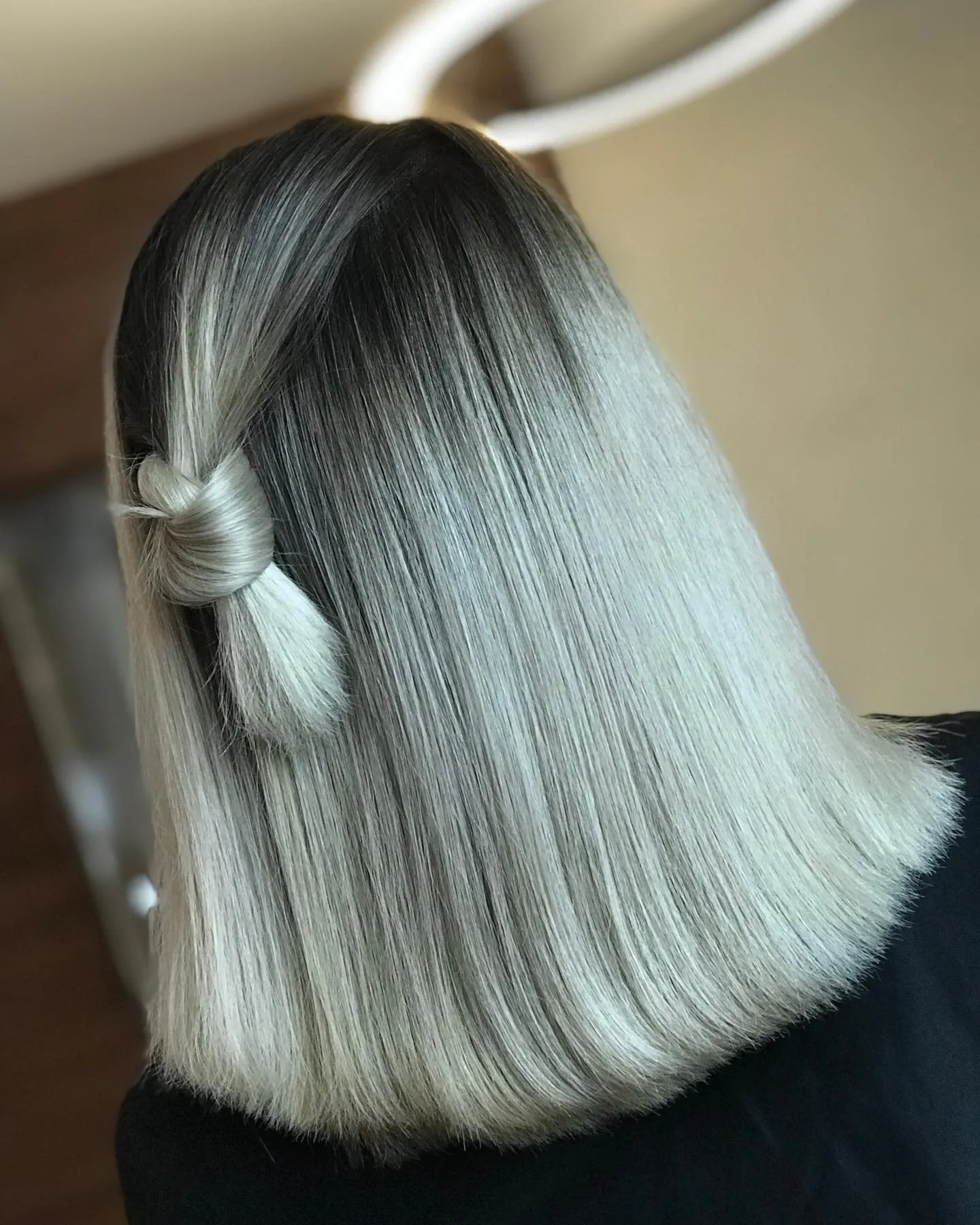 Silver blonde blunt bob with dark roots and side knot