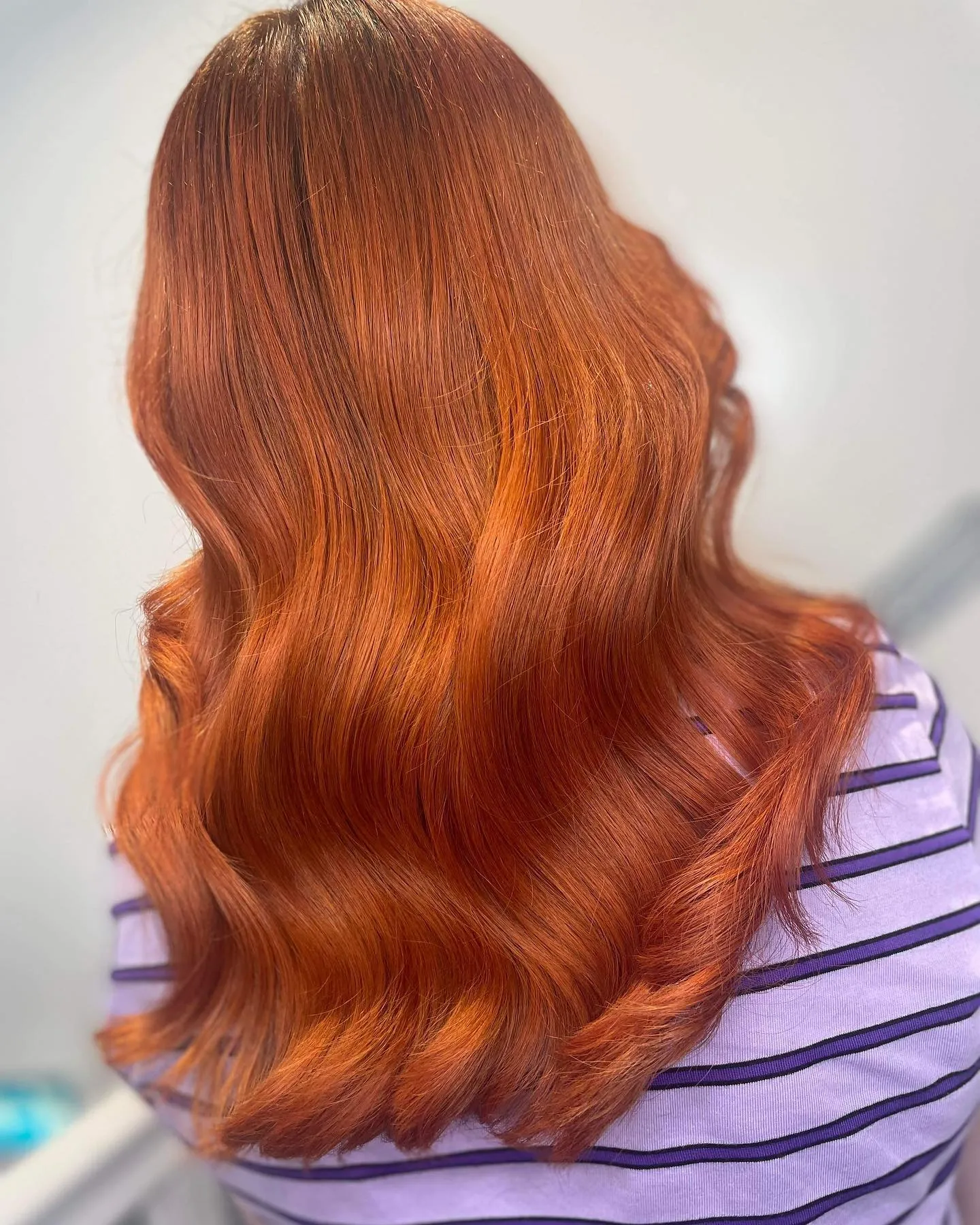 Bright copper amber hair styled in glossy waves
