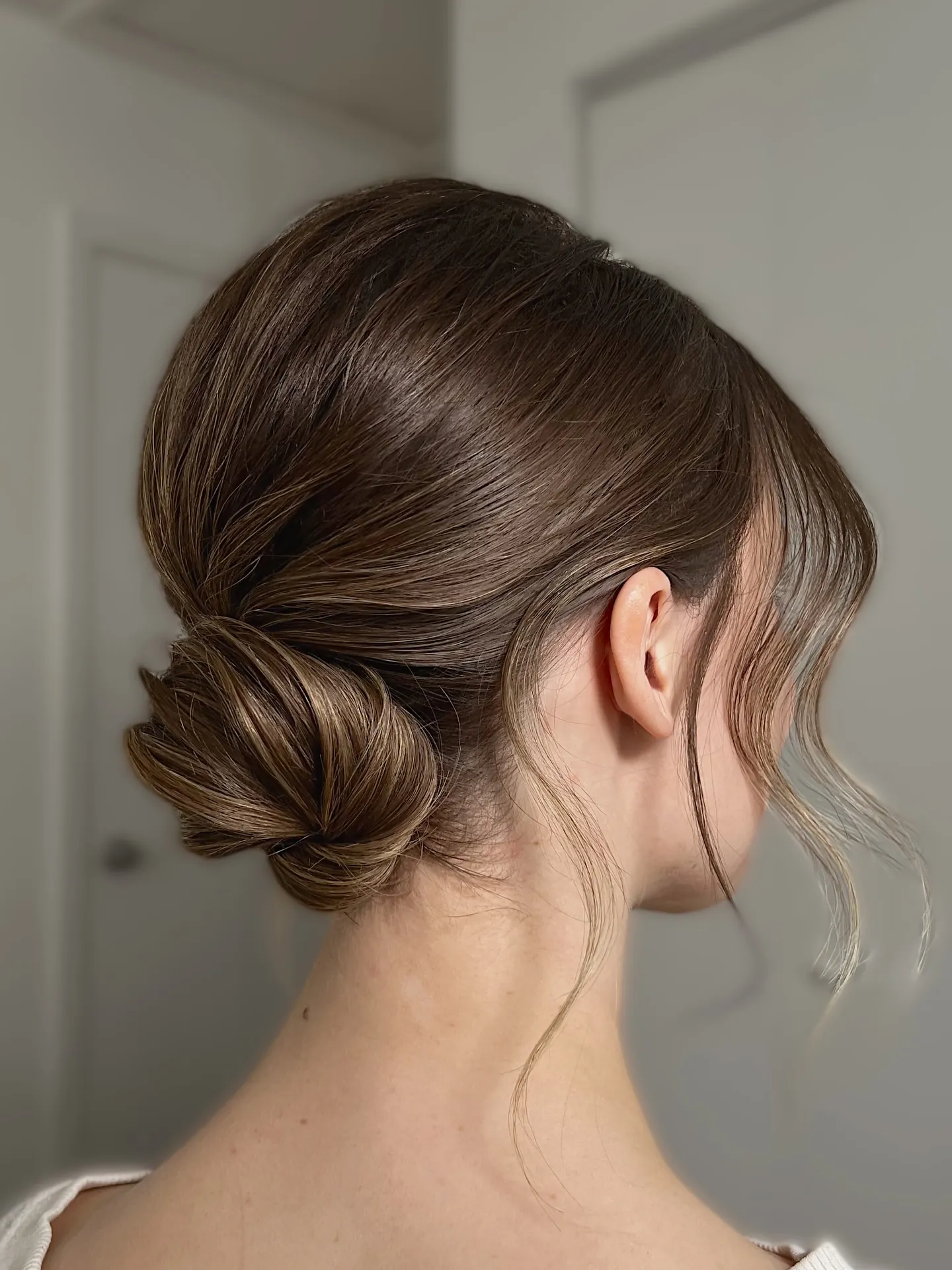 Smooth low bun with face-framing strands