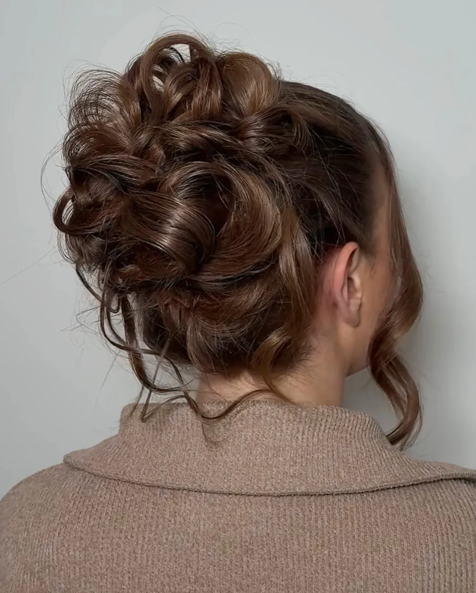 Curly pinned updo bun with loose tendrils