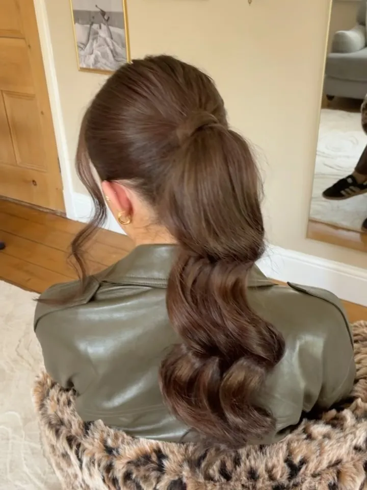Glossy brunette ponytail with large polished waves