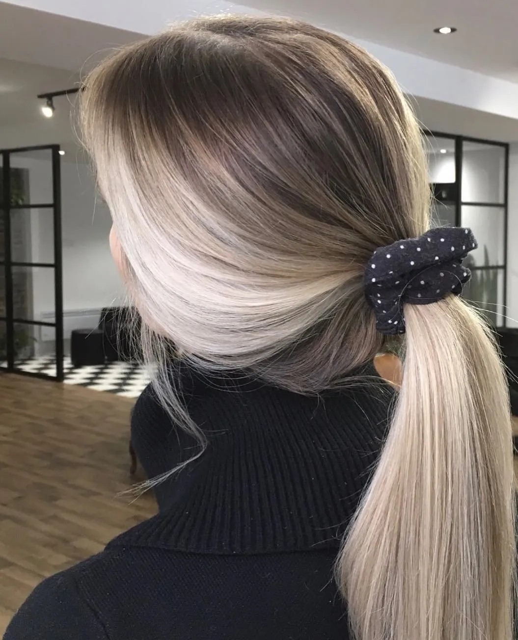 Low blonde ponytail secured with a dark scrunchie
