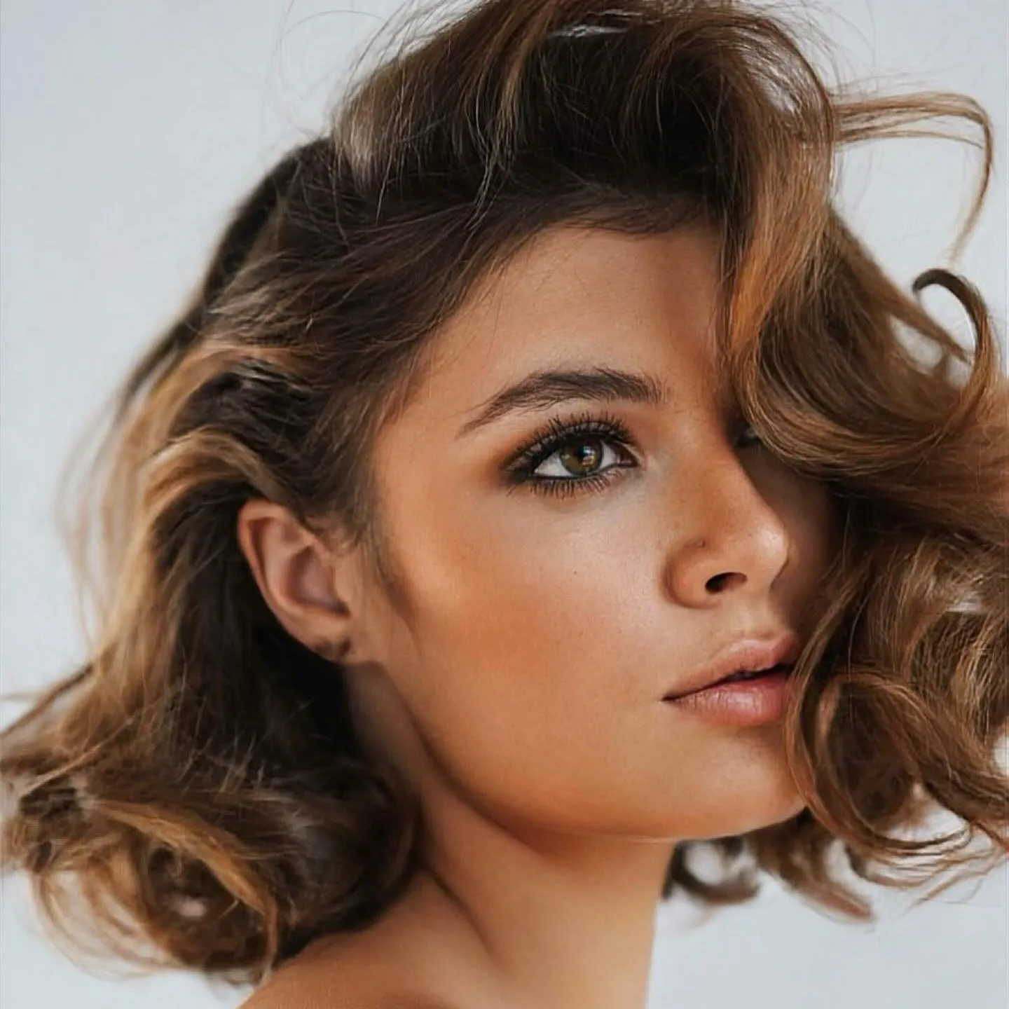 Brunette sculpted bob with side-swept curls and pinned side