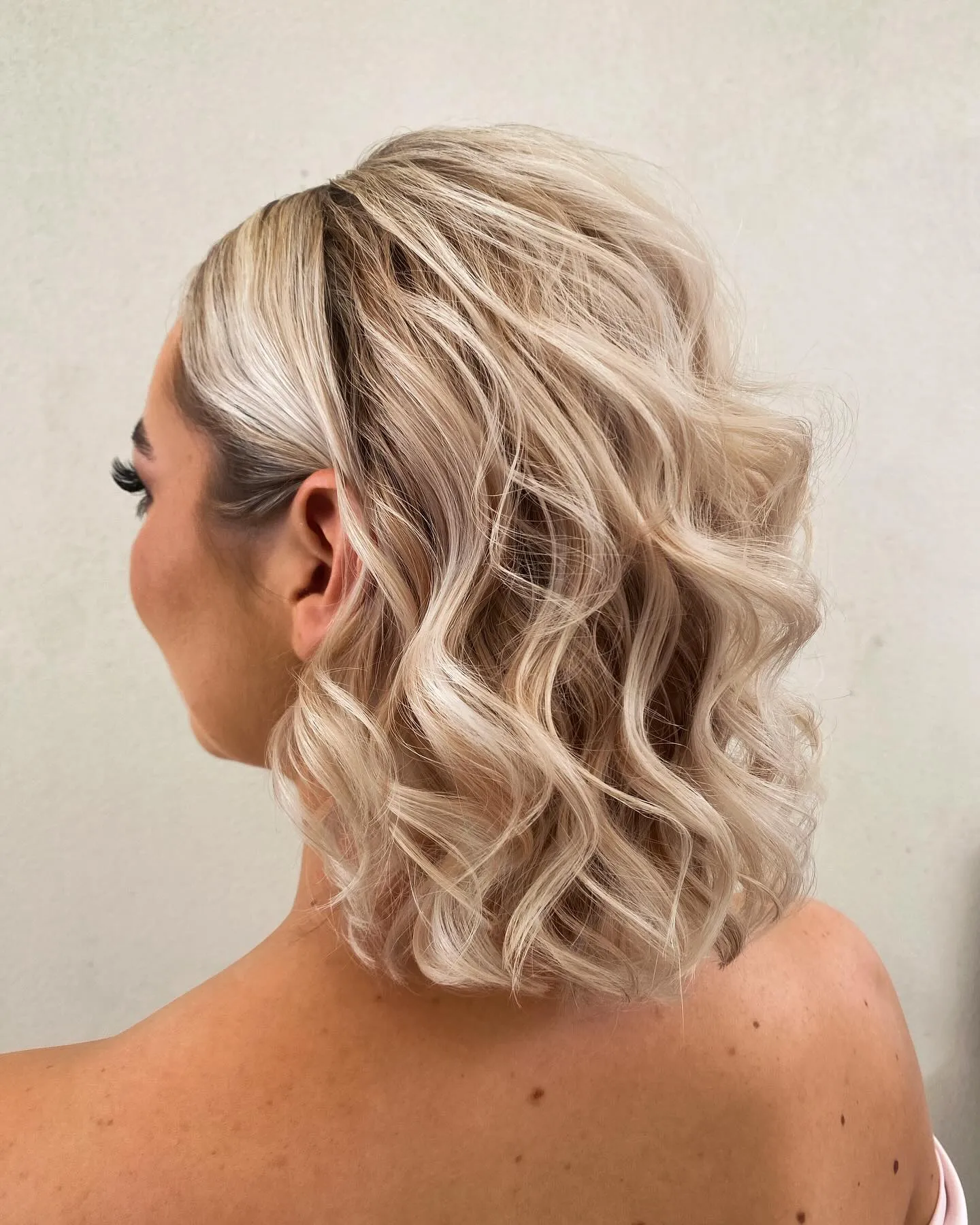 Short tousled blonde bob styled with loose beachy waves