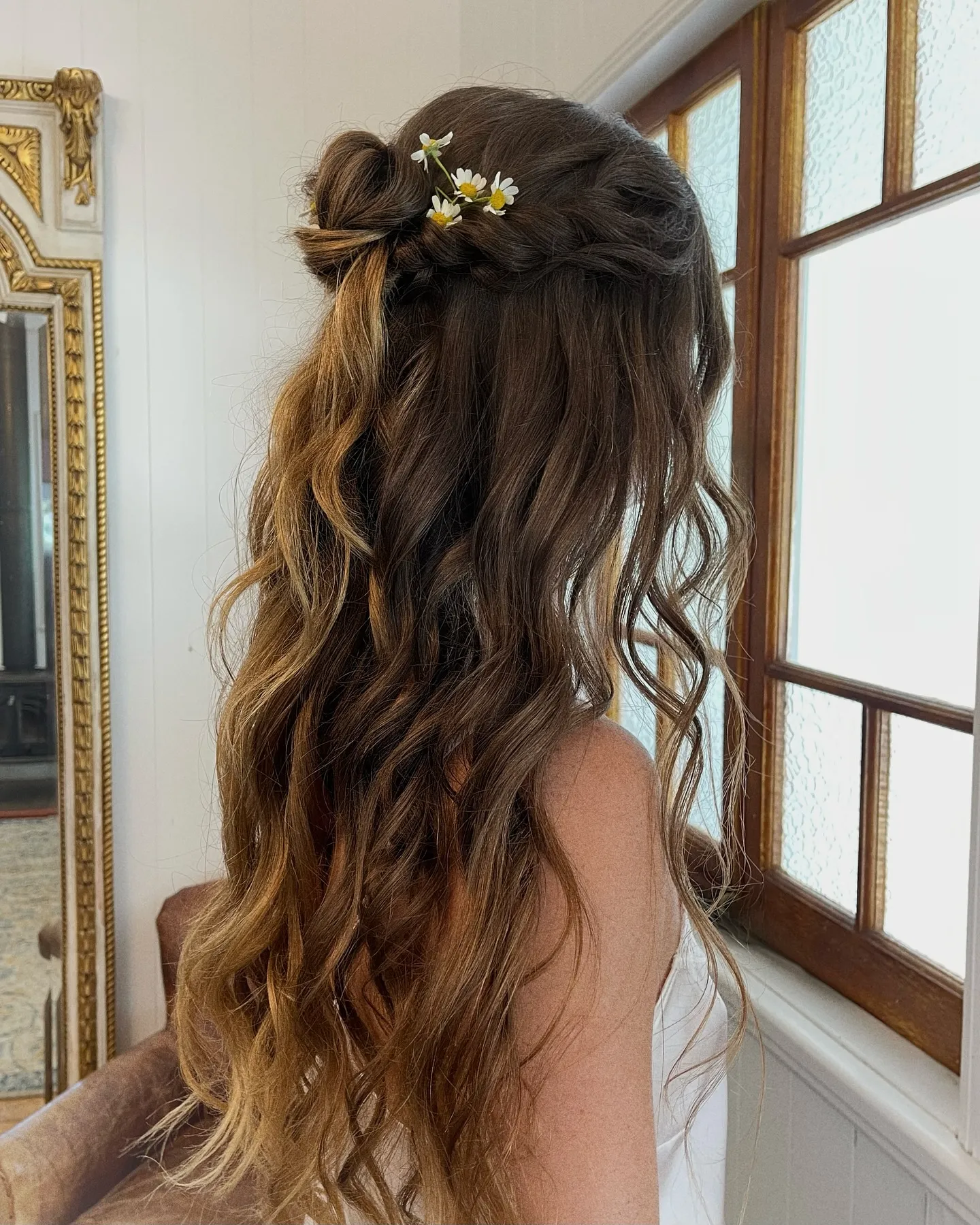 Long half-up waves with small daisy flowers tucked into the twists