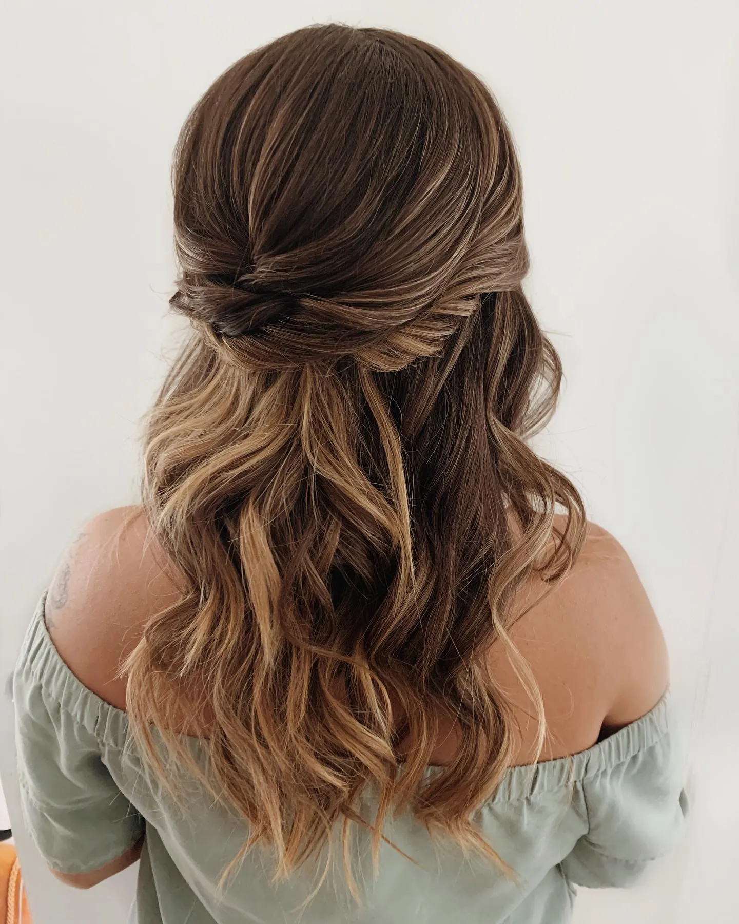 Knotted half-up hairstyle with long soft brunette waves