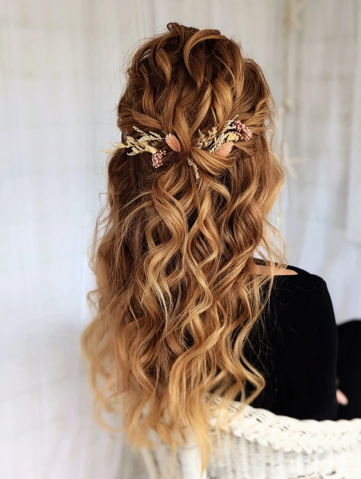 Twisted half-up hairstyle with long defined waves and a floral hair vine