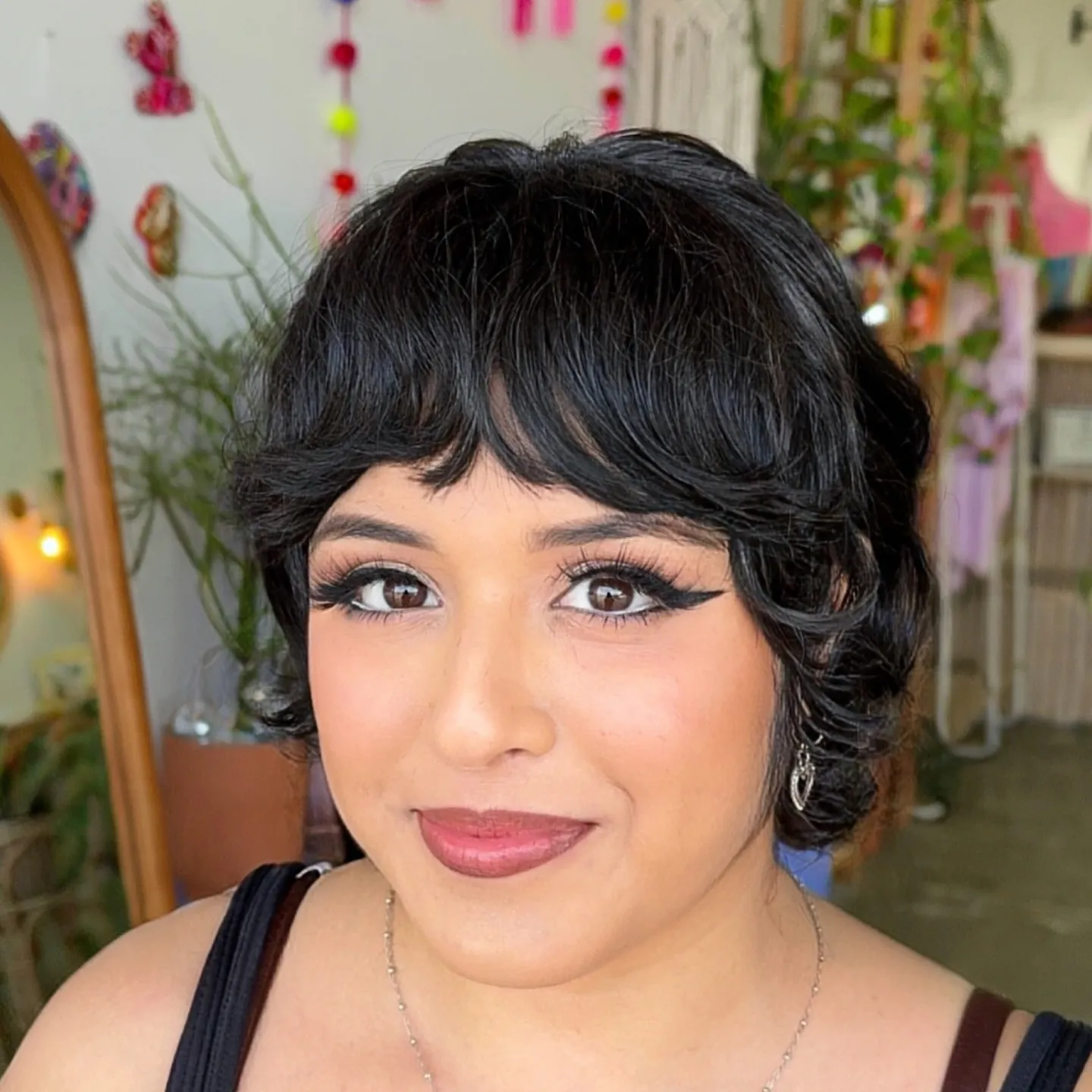 Dark curled bixie with rounded bangs and sculpted side layers