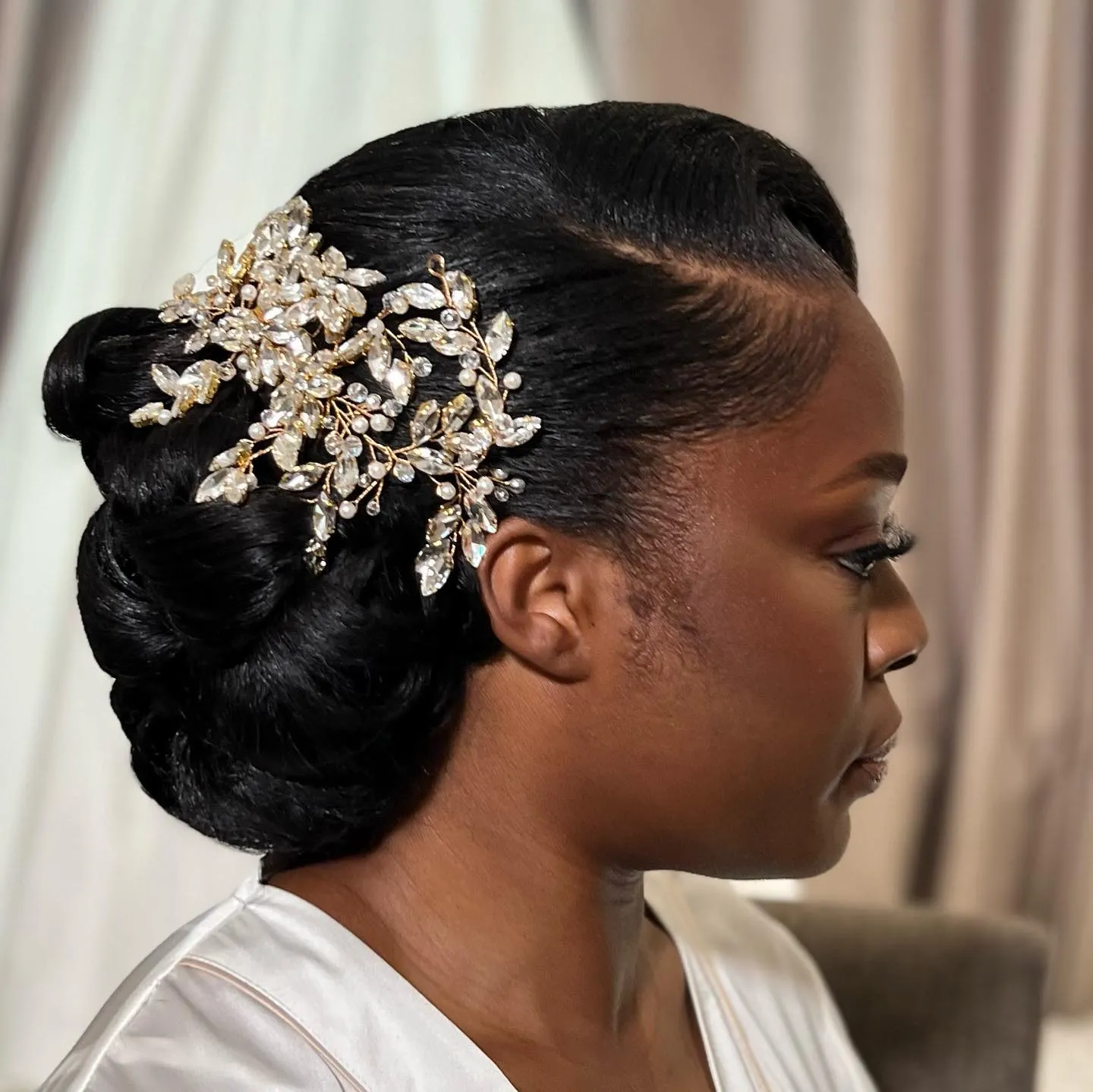Sleek low bridal chignon with a large crystal floral hair comb