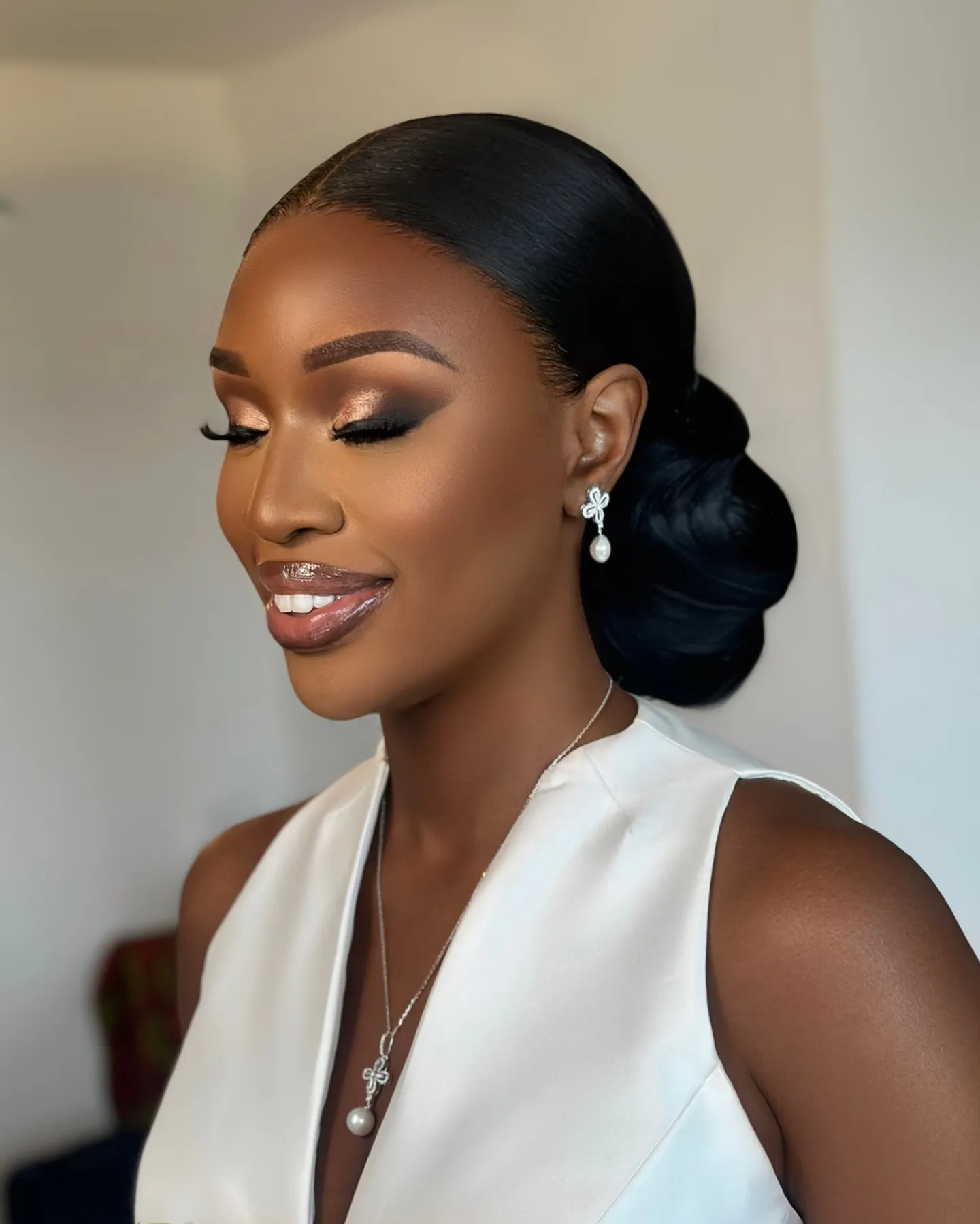 Sleek side-parted bridal hair with a smooth rounded low bun