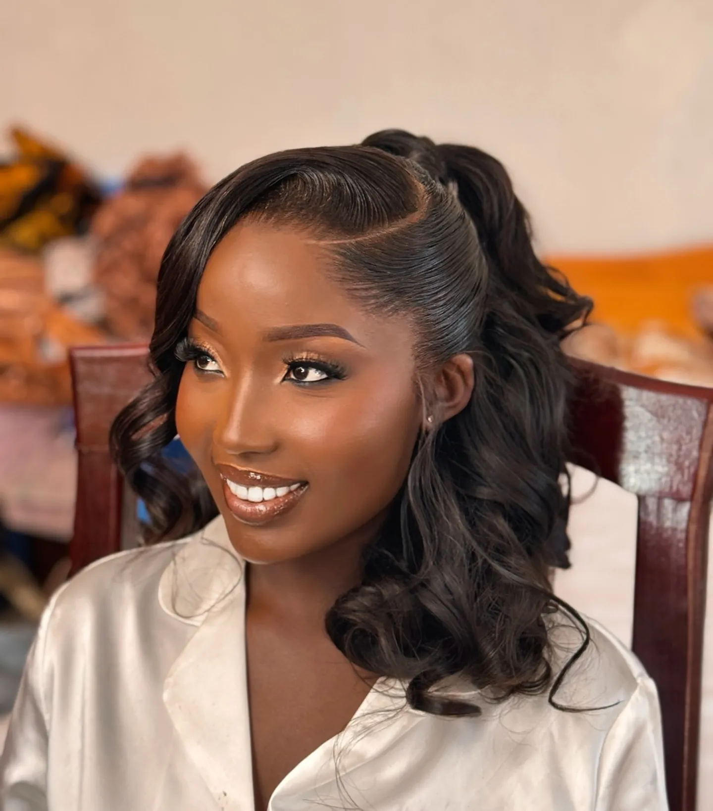 Curled high bridal ponytail with sculpted side part and swooped fringe