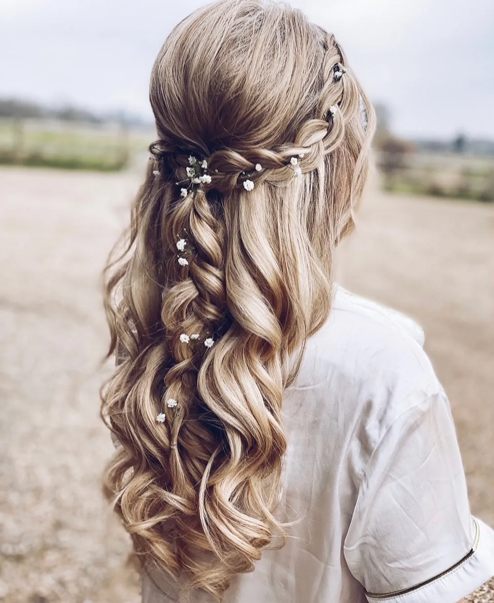 Twisted half-up boho bridal hair with long waves and tiny white flowers