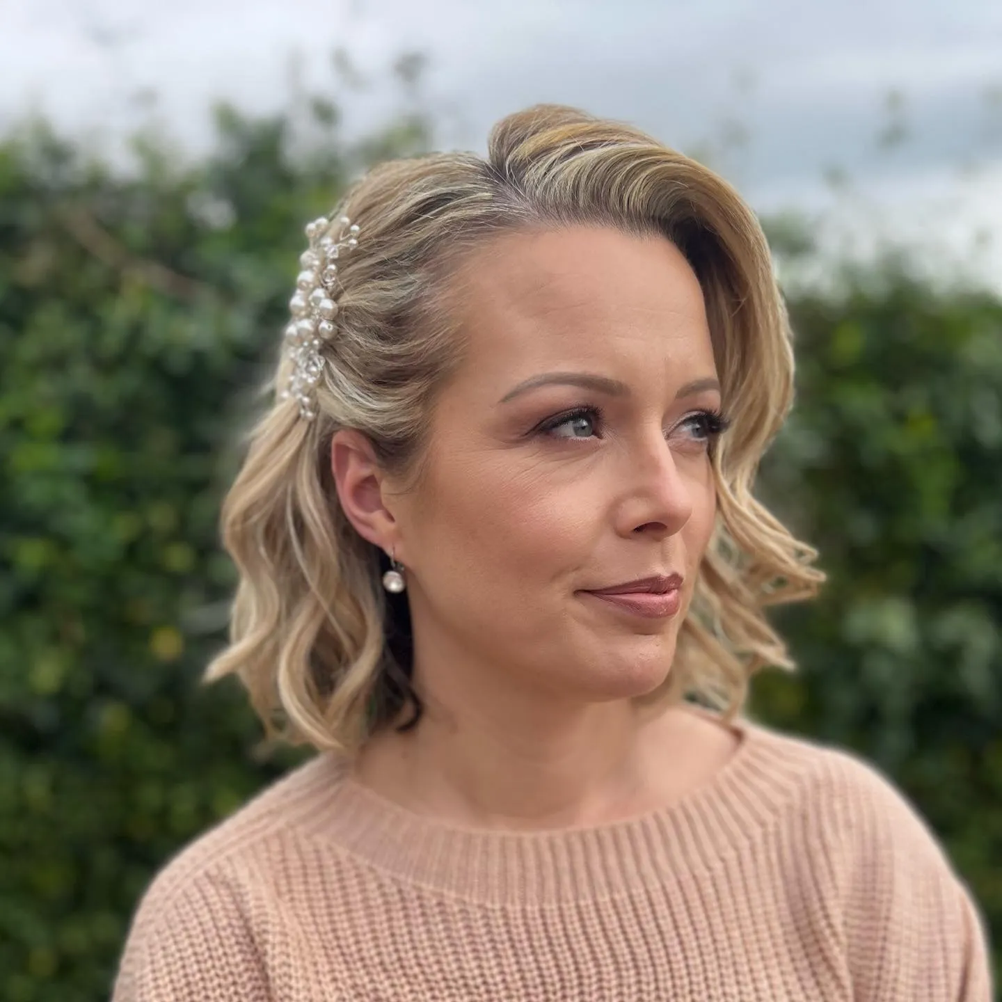 Side-swept wavy bridal bob with pearl barrette and tucked side