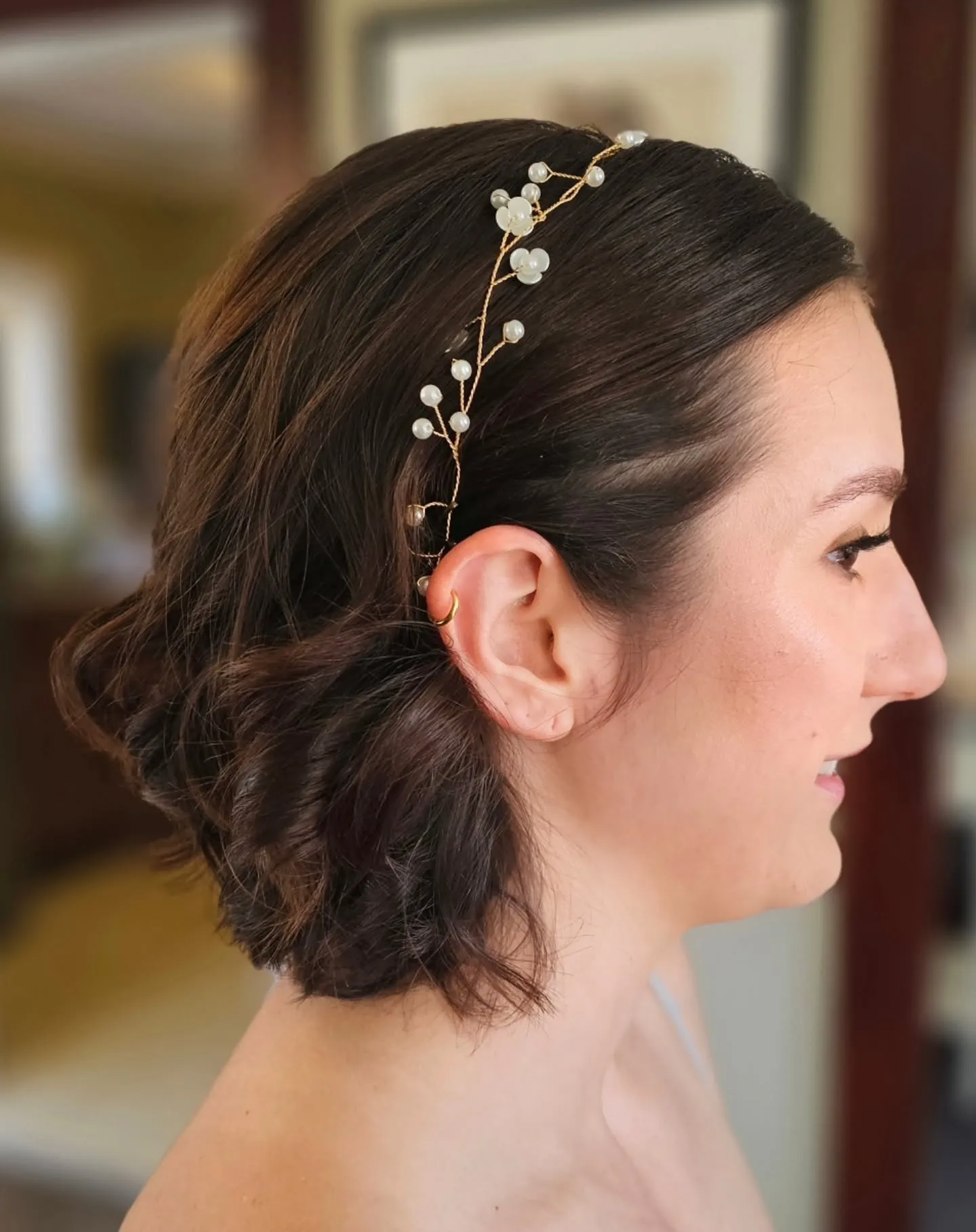 Low pinned bridal bob with textured twists and a delicate floral pearl vine