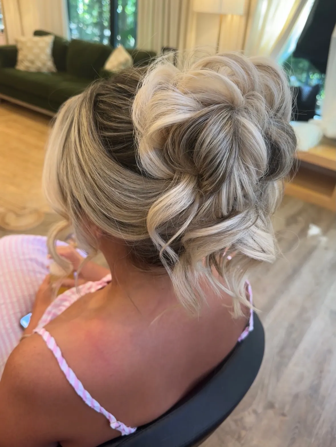 Loose textured high bun with curled face-framing tendrils