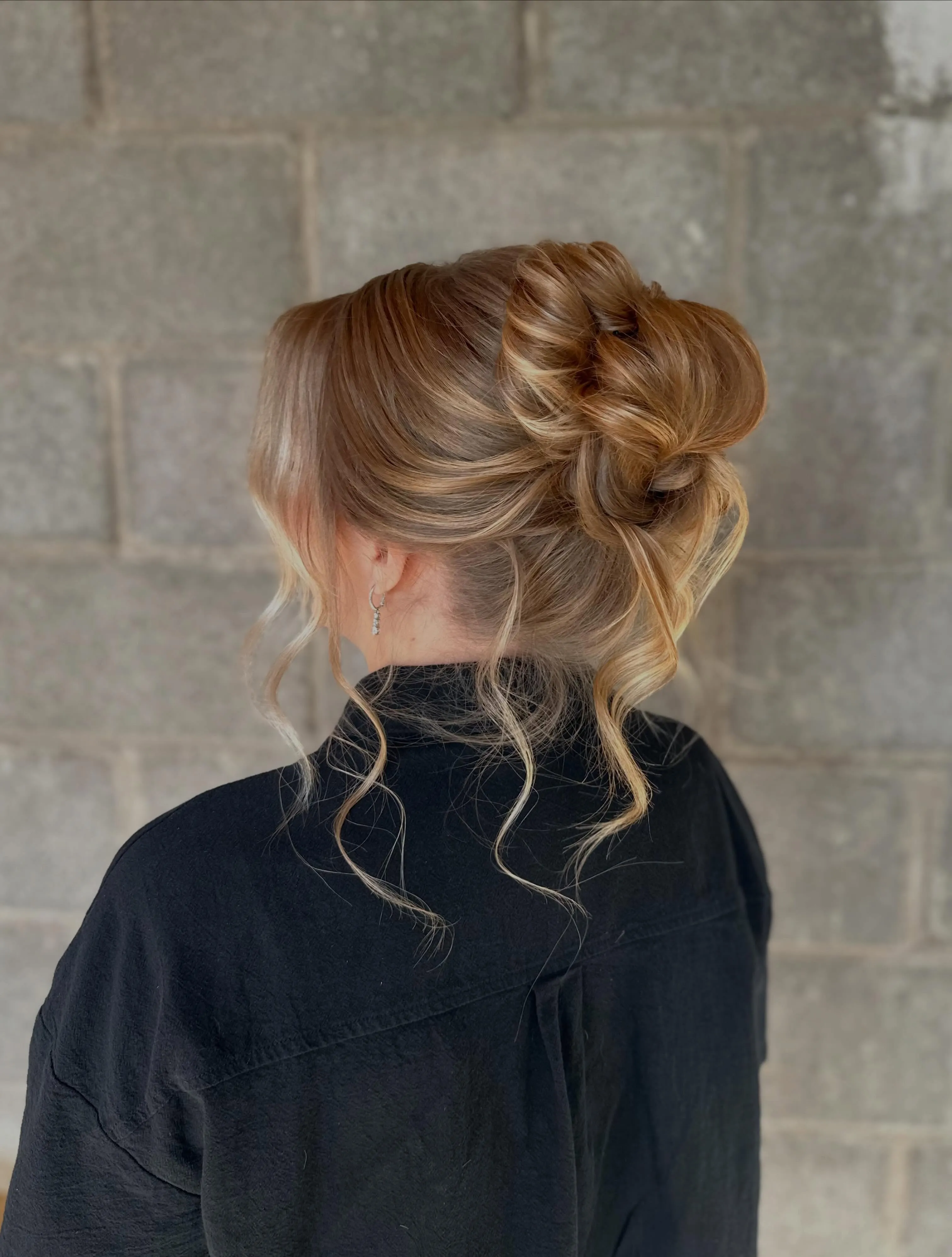 Soft low updo with long curled face-framing tendrils