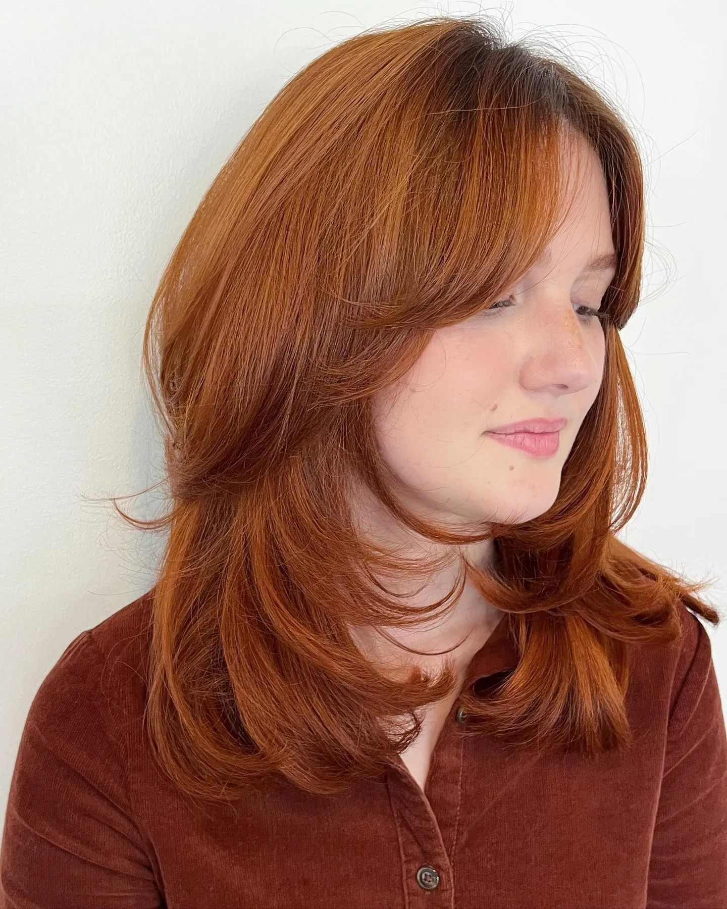 Copper shoulder-length butterfly haircut with curtain layers
