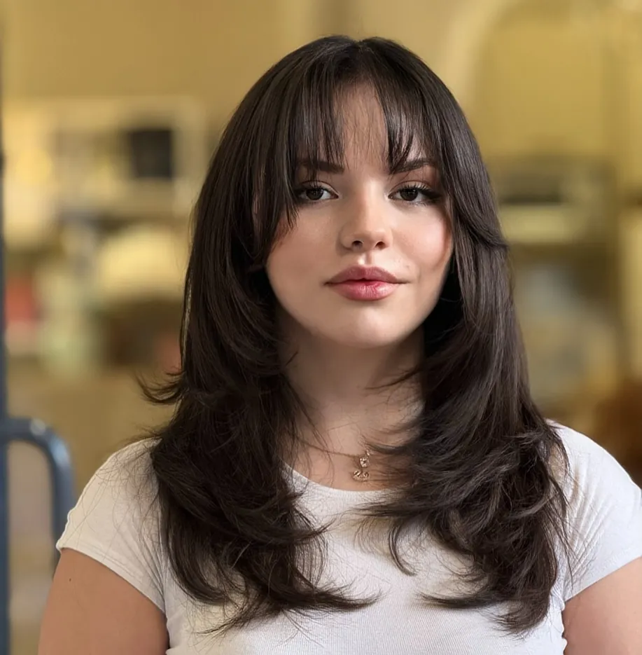 Brunette butterfly haircut with wispy bangs and flipped layers