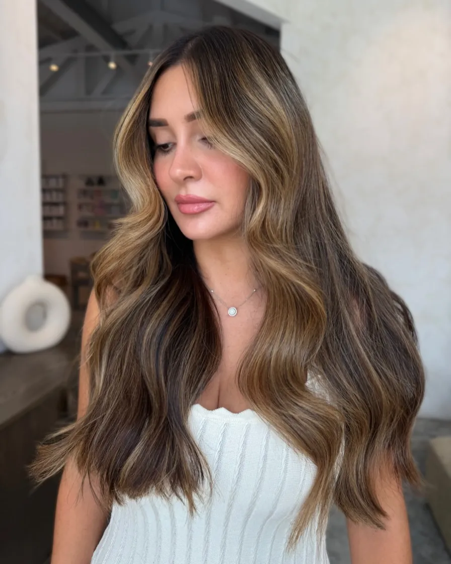 Long brunette waves with dimensional warm ribbon highlights