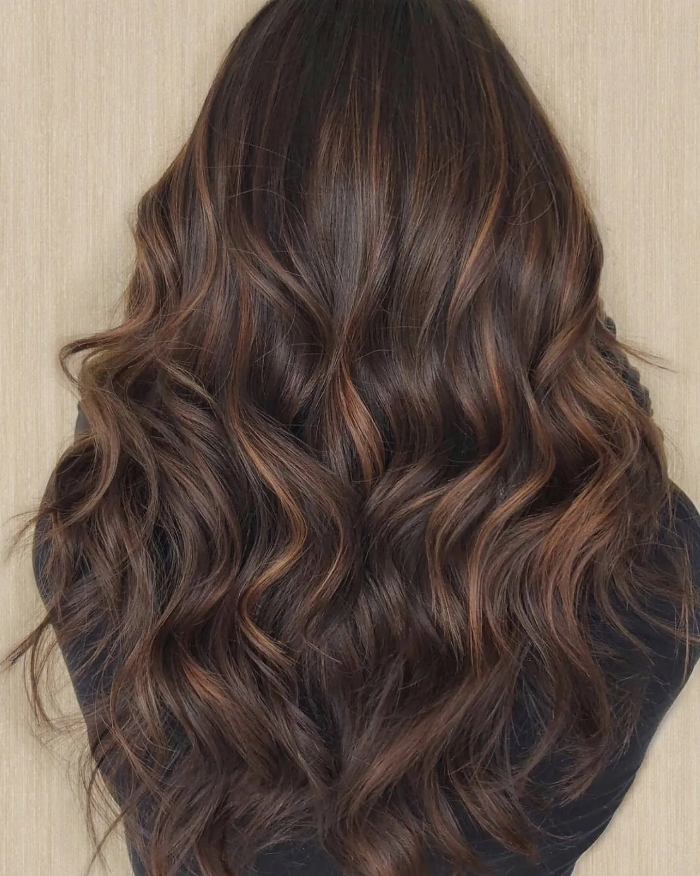 Dark brunette waves with subtle warm ribbon highlights