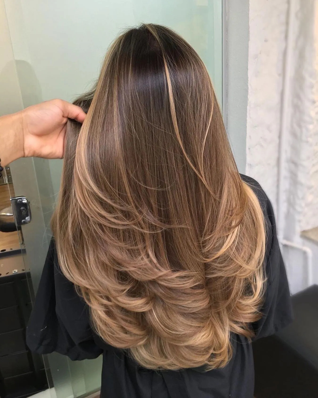 Layered brunette hair with golden balayage through the ends