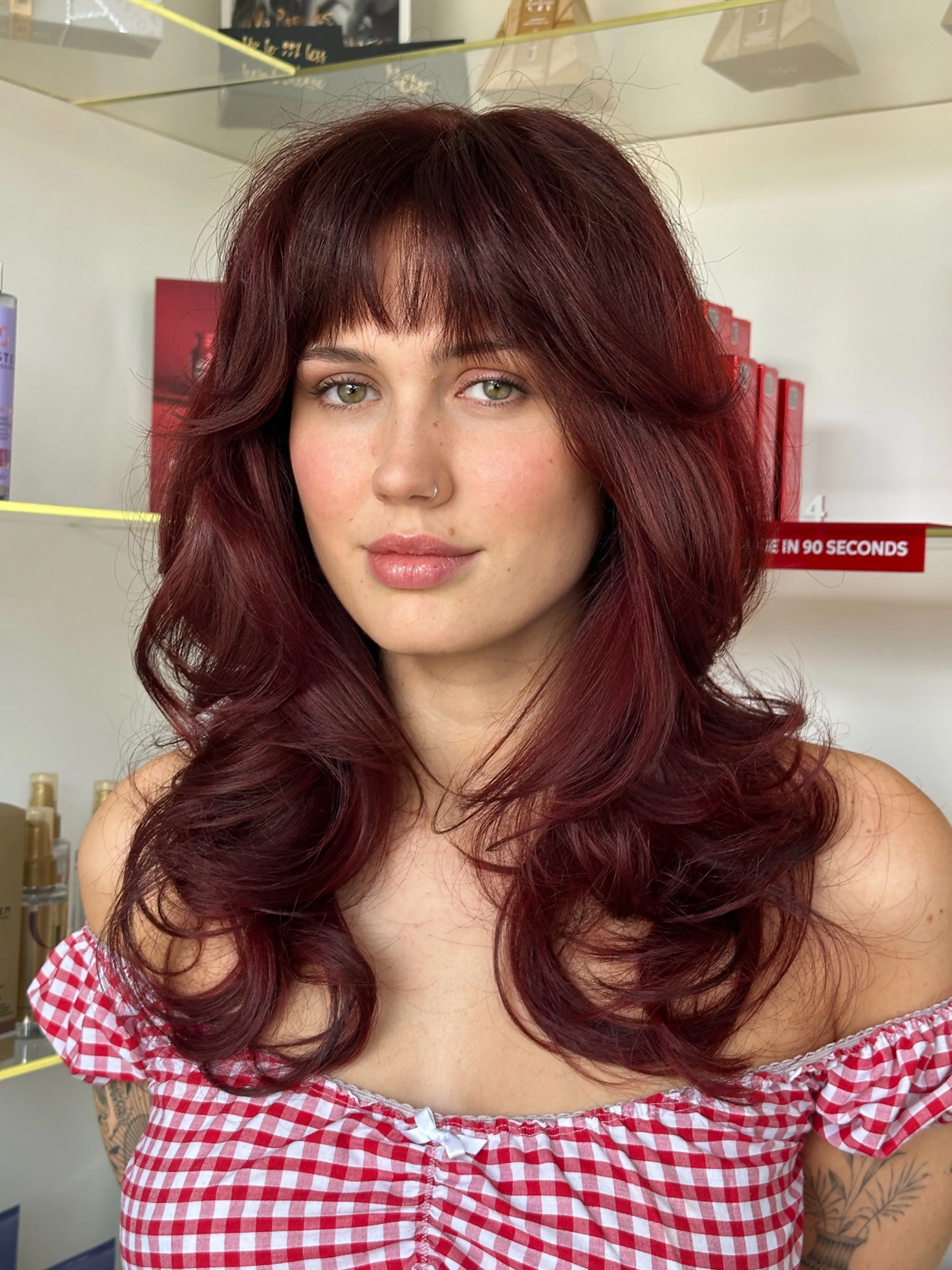 Medium layered shag with curtain bangs in a soft deep red shade
