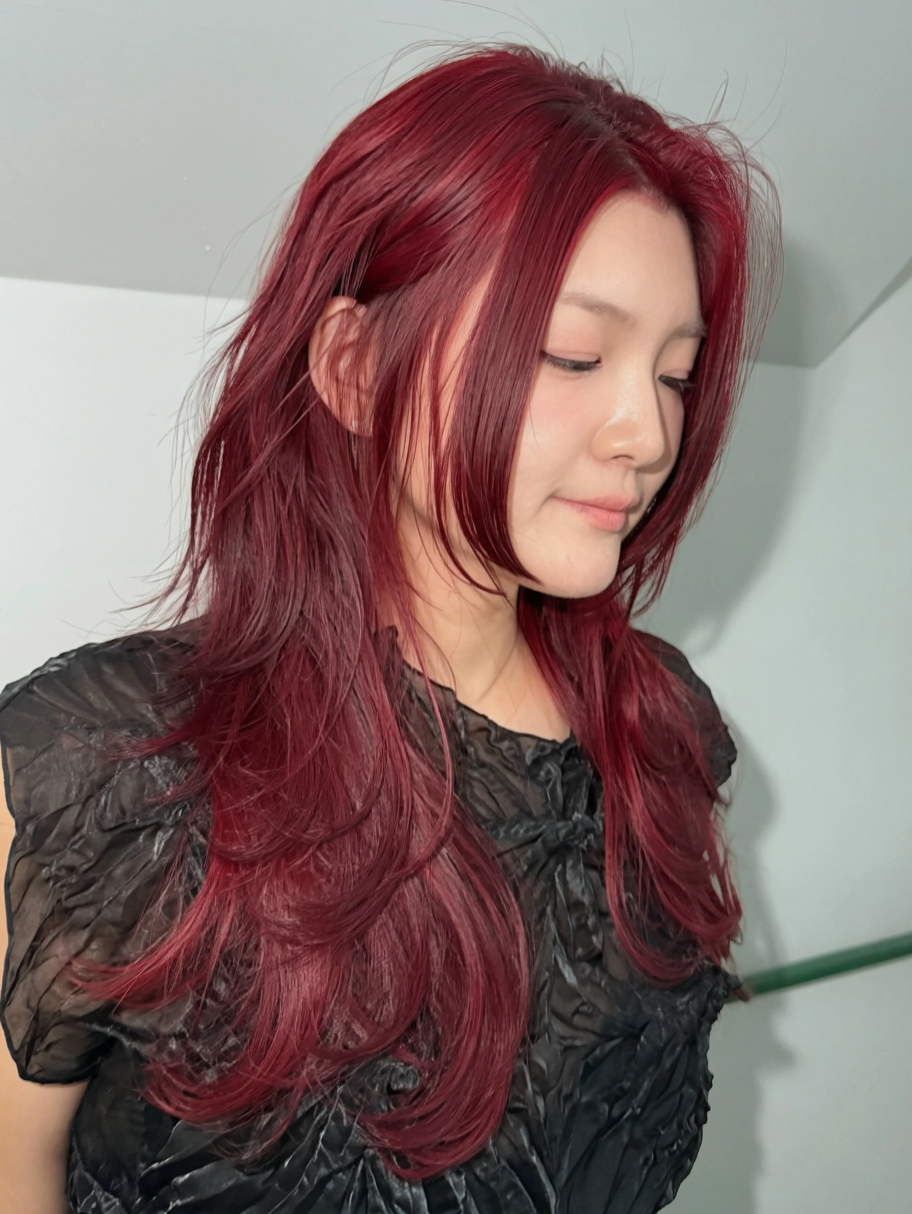 Long layered hair in a bright red shade with face-framing pieces
