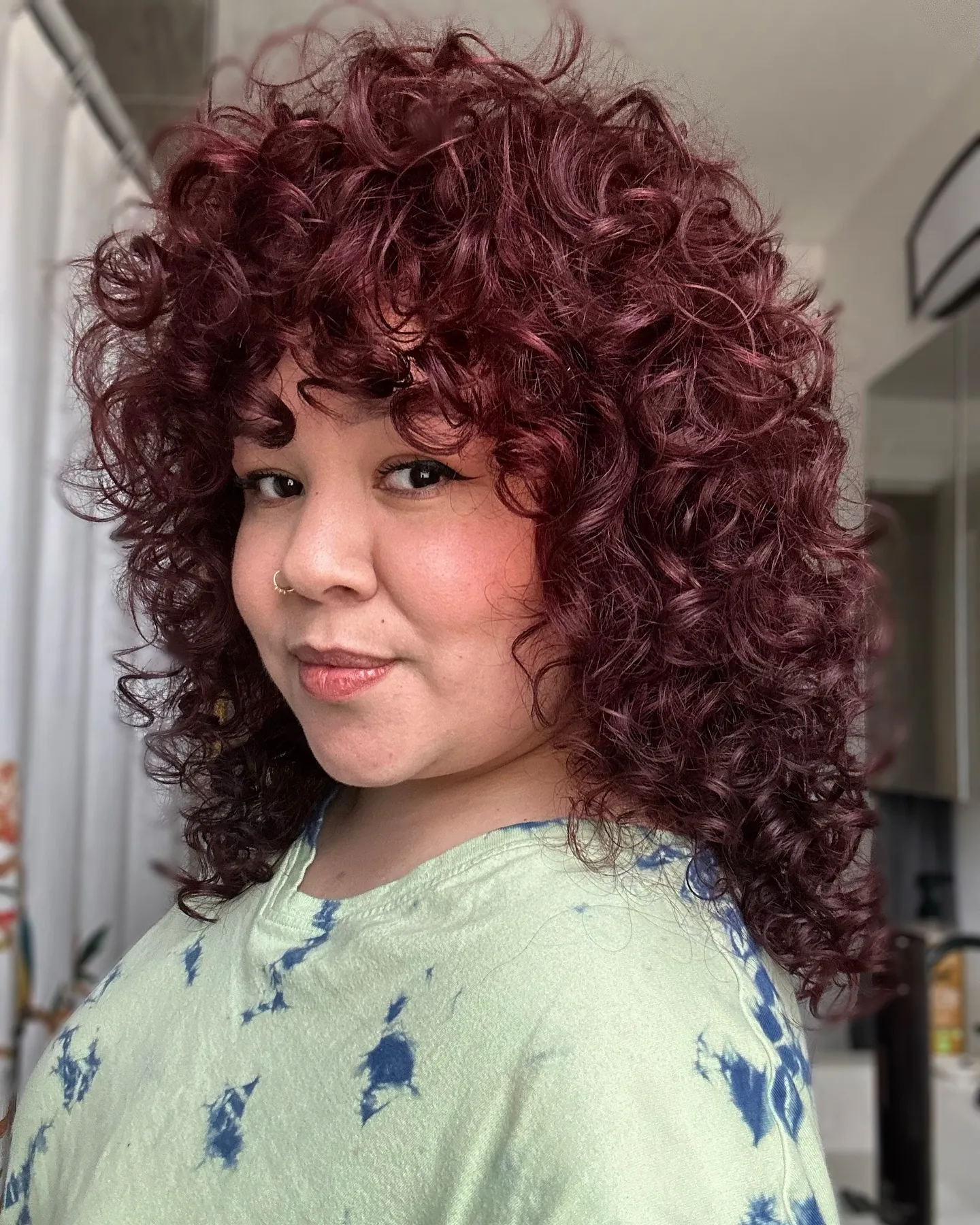 Curly shag haircut with rounded burgundy red curls and fringe