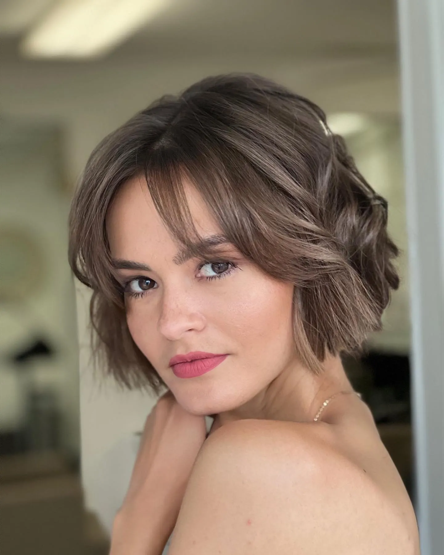Soft wavy chin-length bob with curtain fringe and one side pinned back