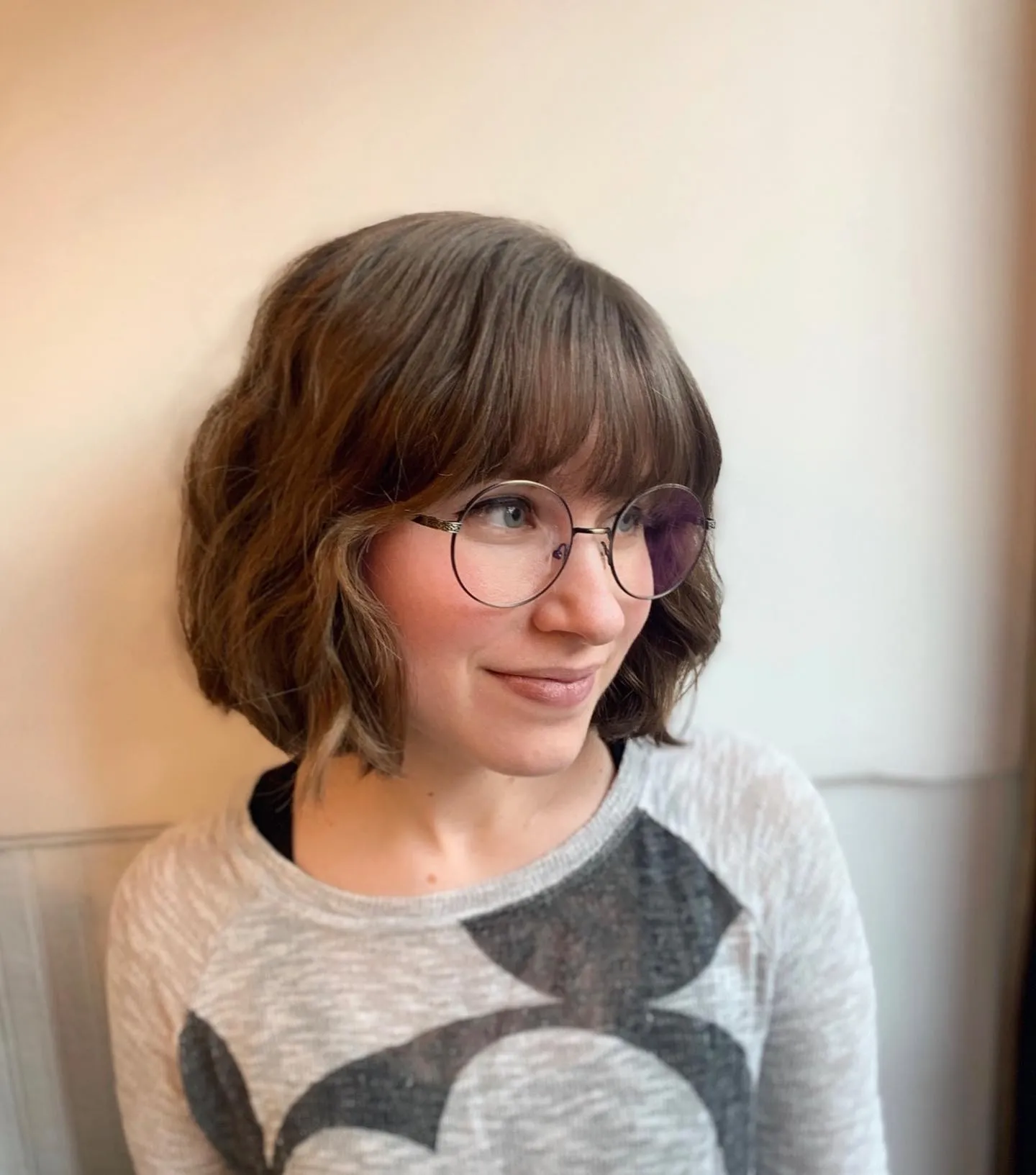 Rounded wavy brown chin-length bob with a full fringe and glasses