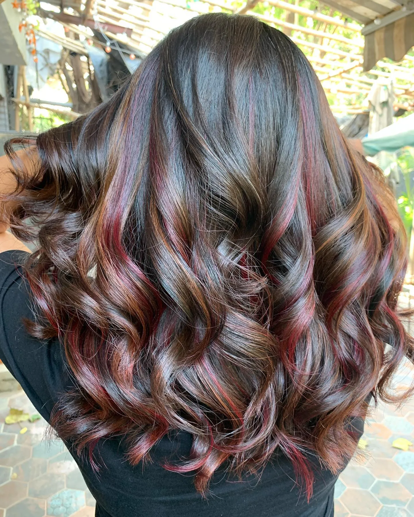 Long dark curls with fine red ribbon highlights