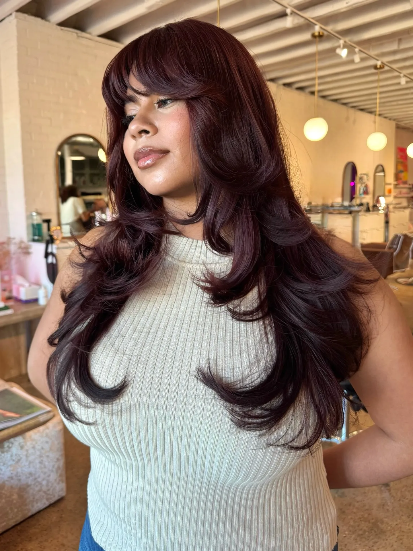 Long feathered haircut with deep burgundy red-brown color and fringe