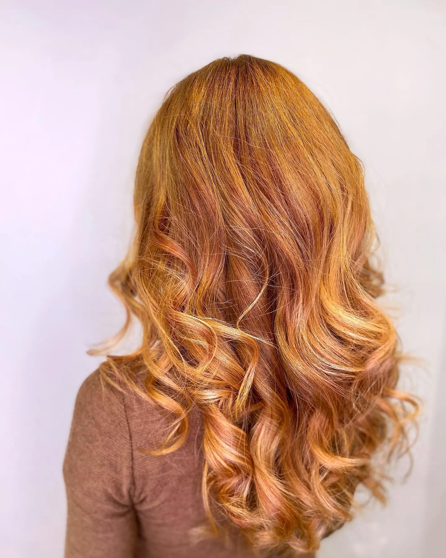 Long light copper balayage styled in soft curls