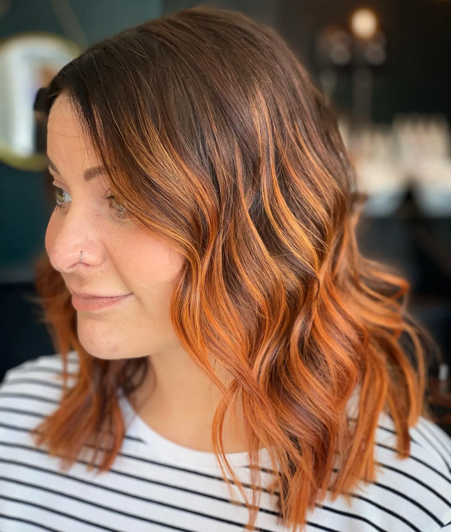 Shoulder-length dark hair with vivid copper face-framing pieces