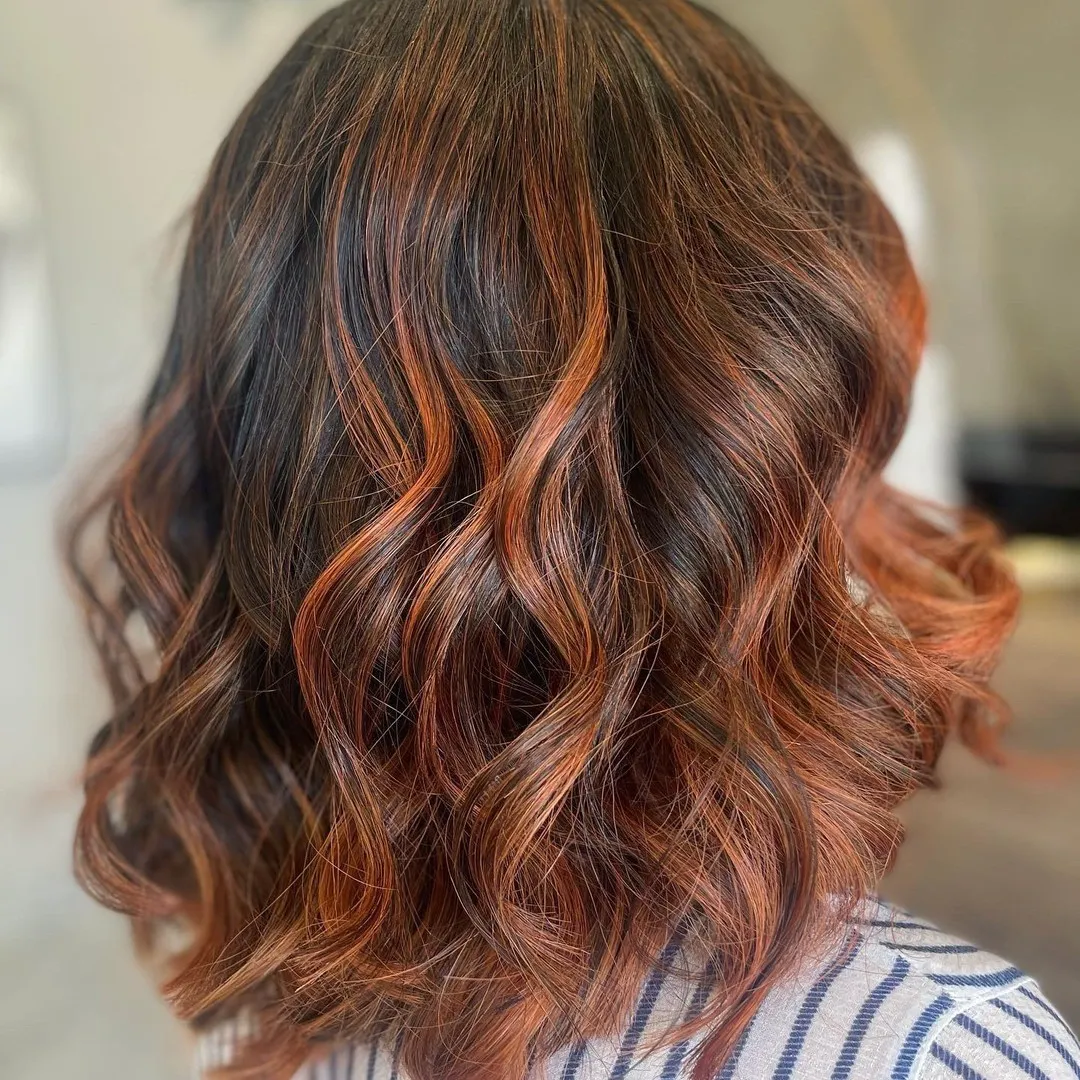 Wavy brunette lob with copper ribbon balayage