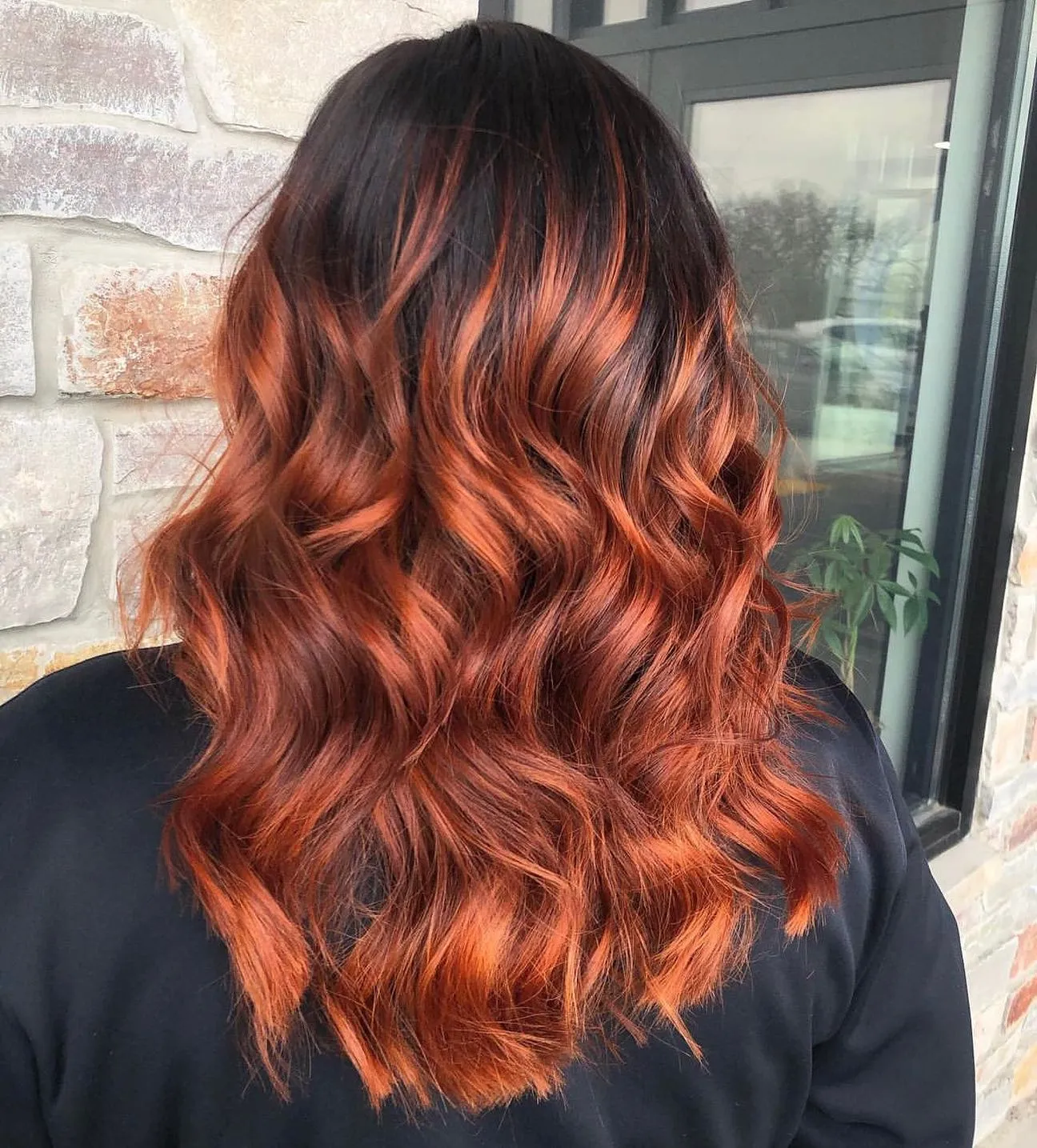 High-contrast copper balayage with dark roots and defined waves