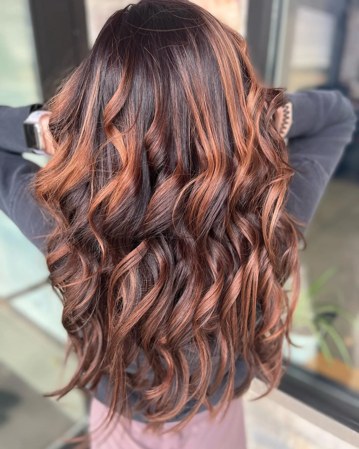 Fine copper ribbons through long dark brown curls